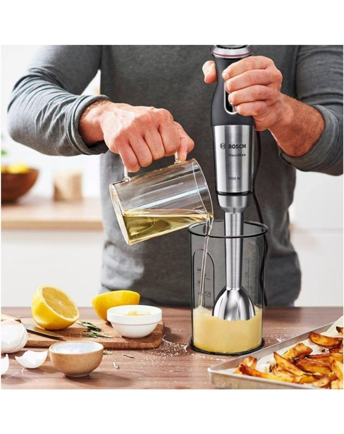 Person verwendet Bosch MaxoMix Stabmixer. Flüssigkeit in ein Glas gießen.