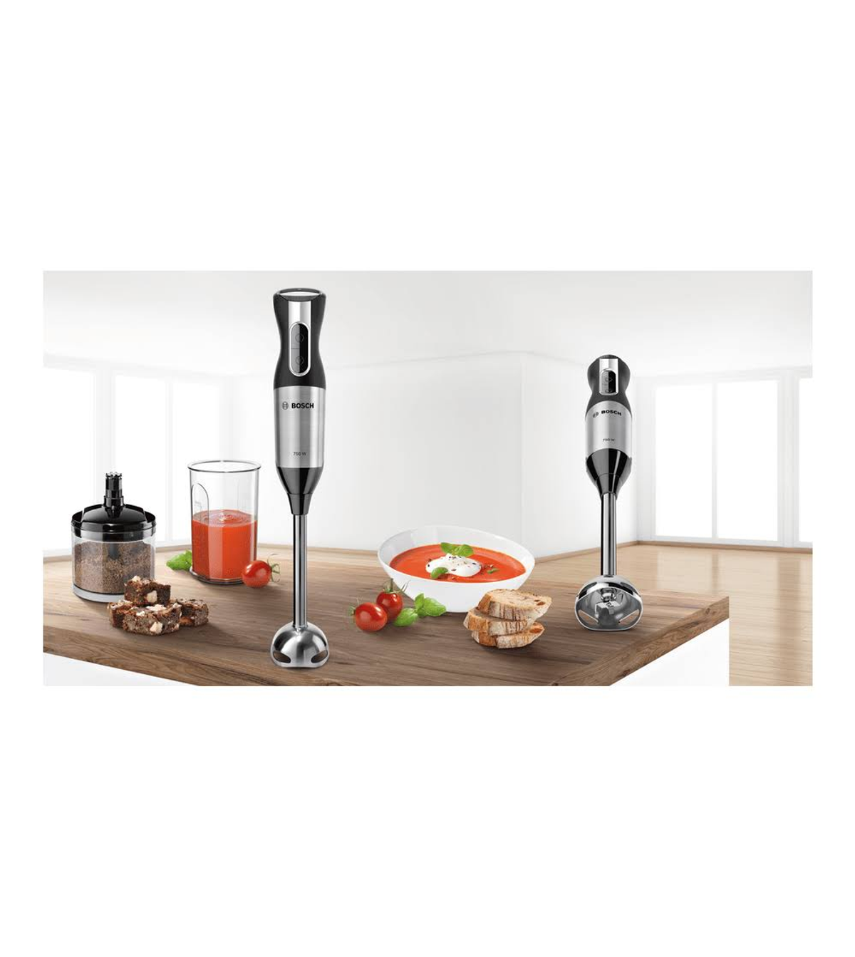 Blender ręczny z akcesoriami. Miska czerwonej zupy, pomidory, chleb i szklanka soku.