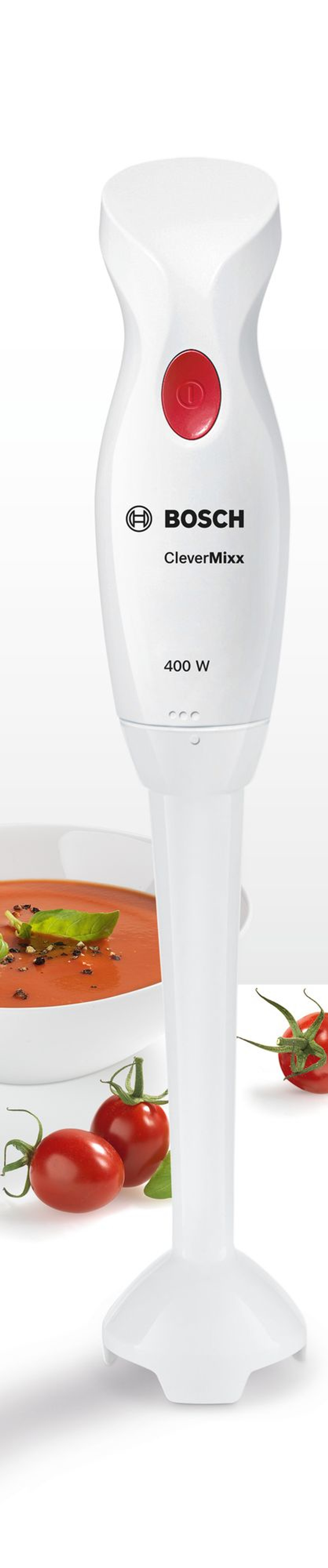 Weißer Stabmixer mit roter Taste, Tomaten und Suppenschüssel auf weißem Hintergrund.