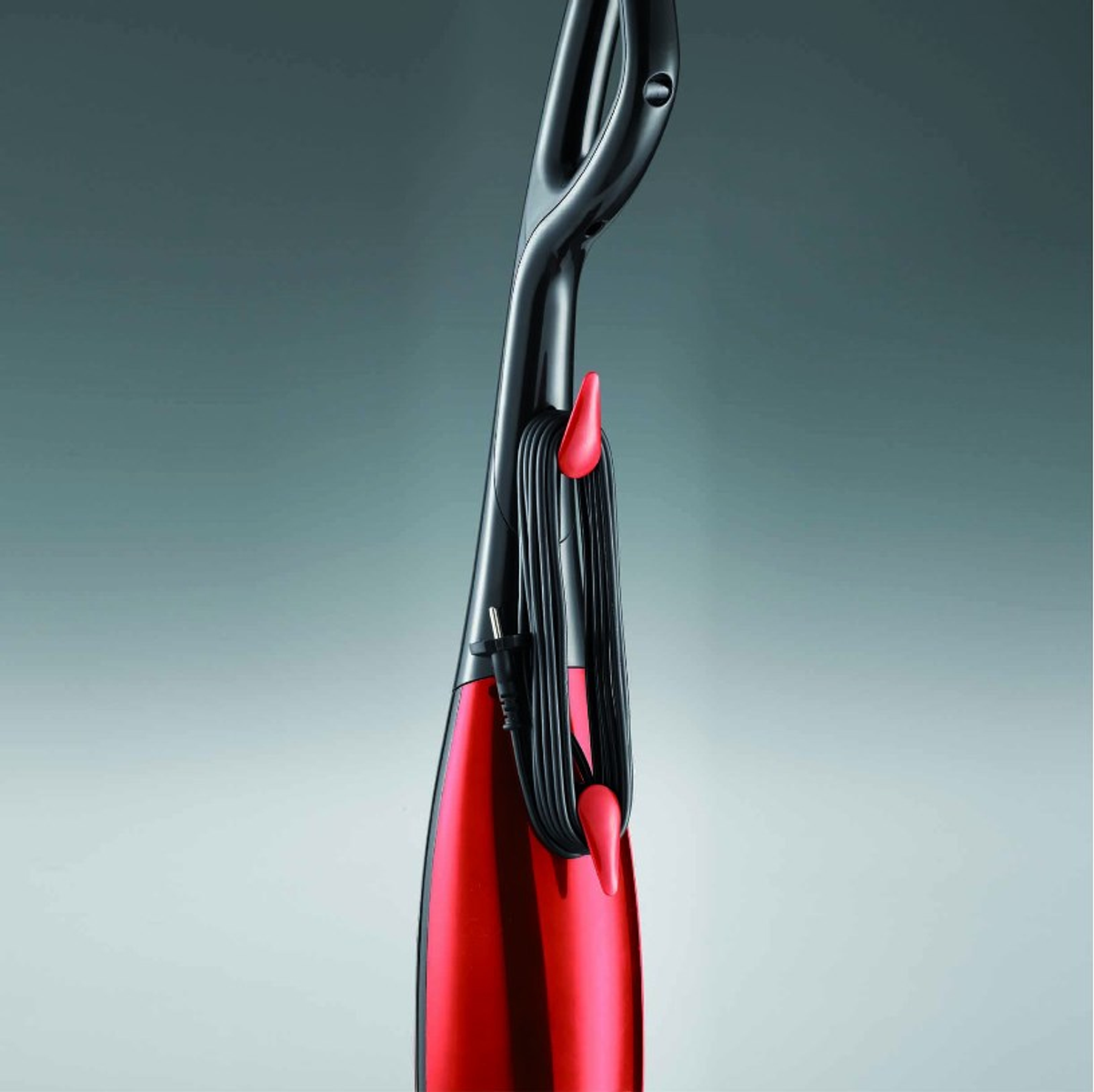 Czerwono-czarny odkurzacz parowy z owiniętym kablem. Na jasnoszarym tle.