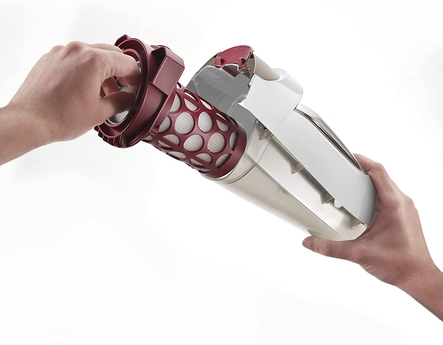 Ręce demontują pojemnik na kurz odkurzacza, ujawniając filtr i elementy.