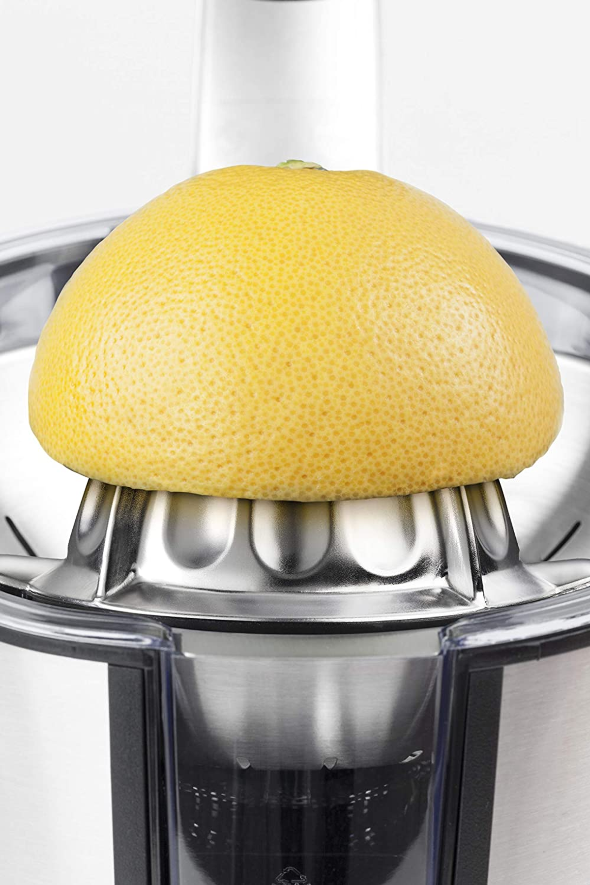 Un pompelmo giallo posto su uno spremiagrumi argentato, vista ravvicinata.