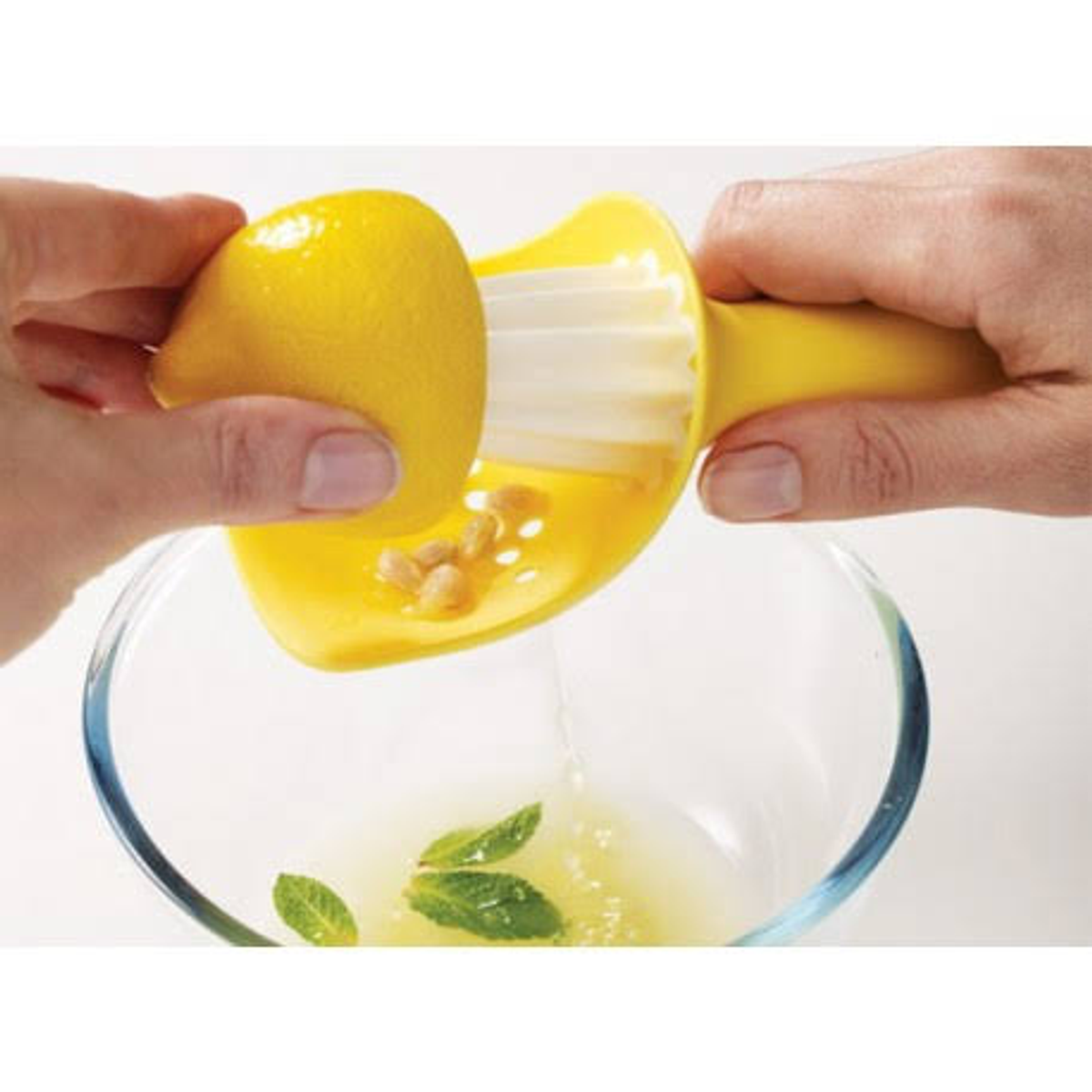Ręce wyciskają cytrynę do miski. Użyto żółtej wyciskarki.