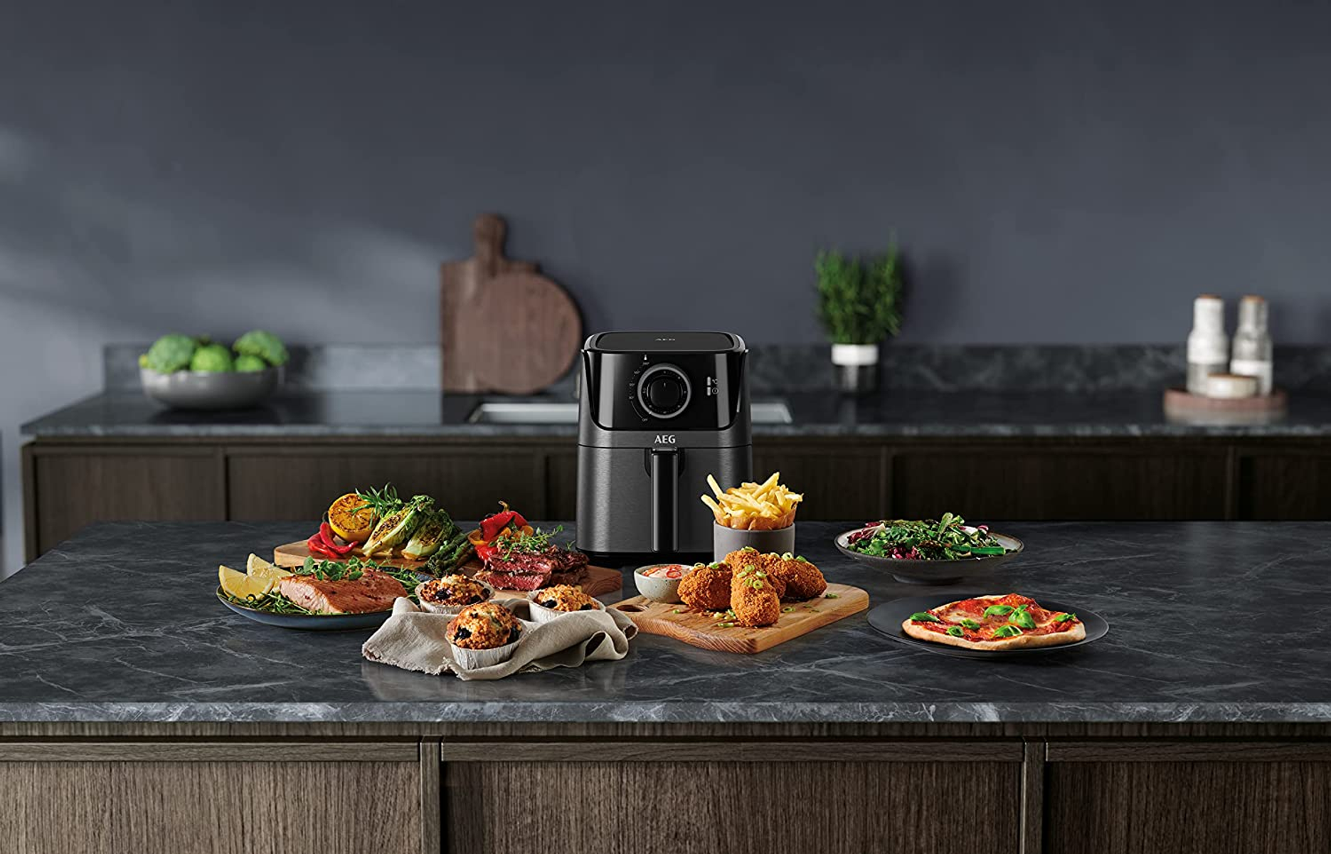 Frytownica beztłuszczowa otoczona ugotowanym jedzeniem. Różne dania. Ciemne tło.