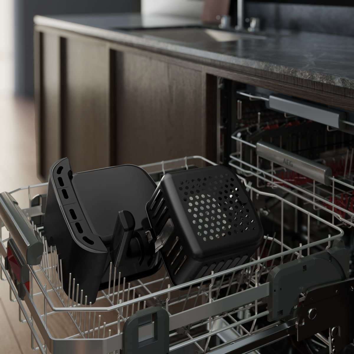 Części frytownicy w zmywarce. Czarne kosze i stojak ze stali nierdzewnej.