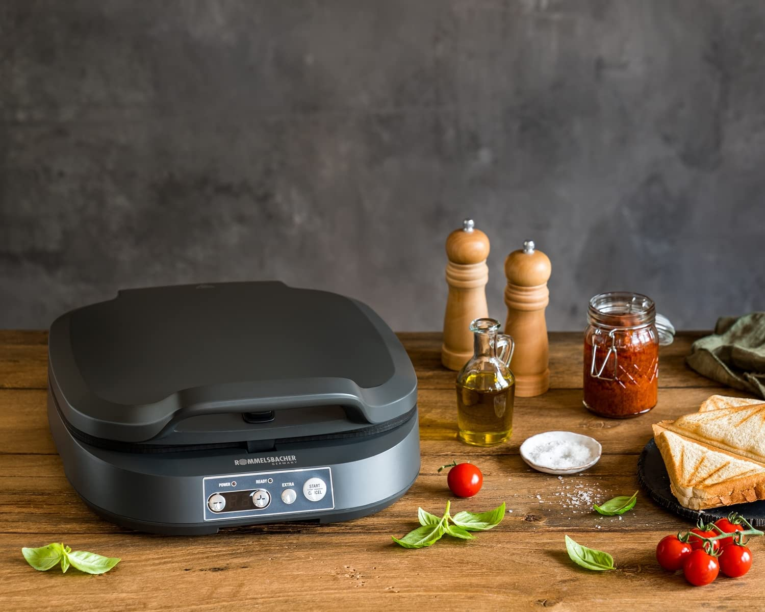 Sandwiczarka ze składnikami na drewnianym stole.