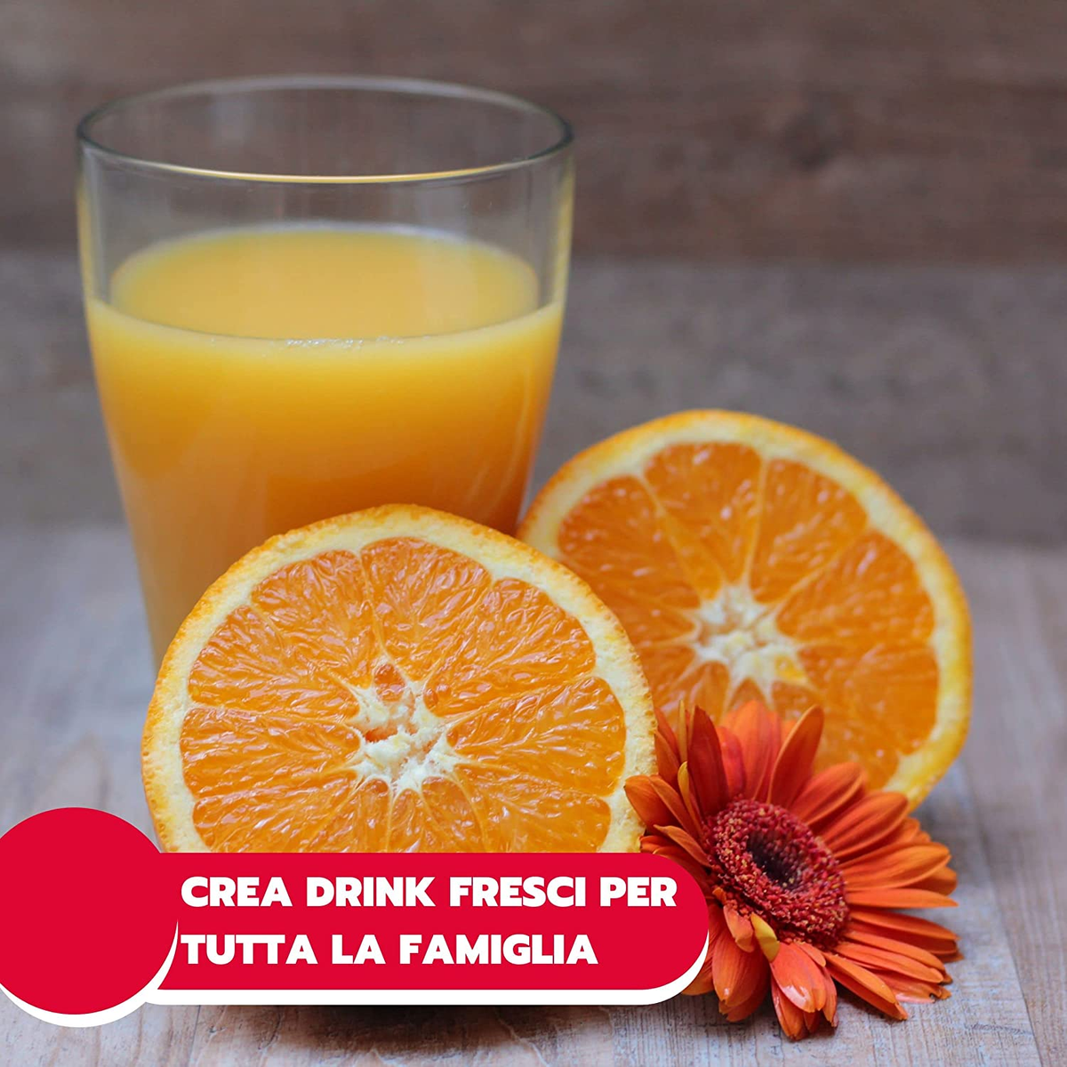 Un bicchiere di succo d'arancia, fette d'arancia e un fiore arancione su una superficie di legno. Il testo dice 'CREA DRINK'.