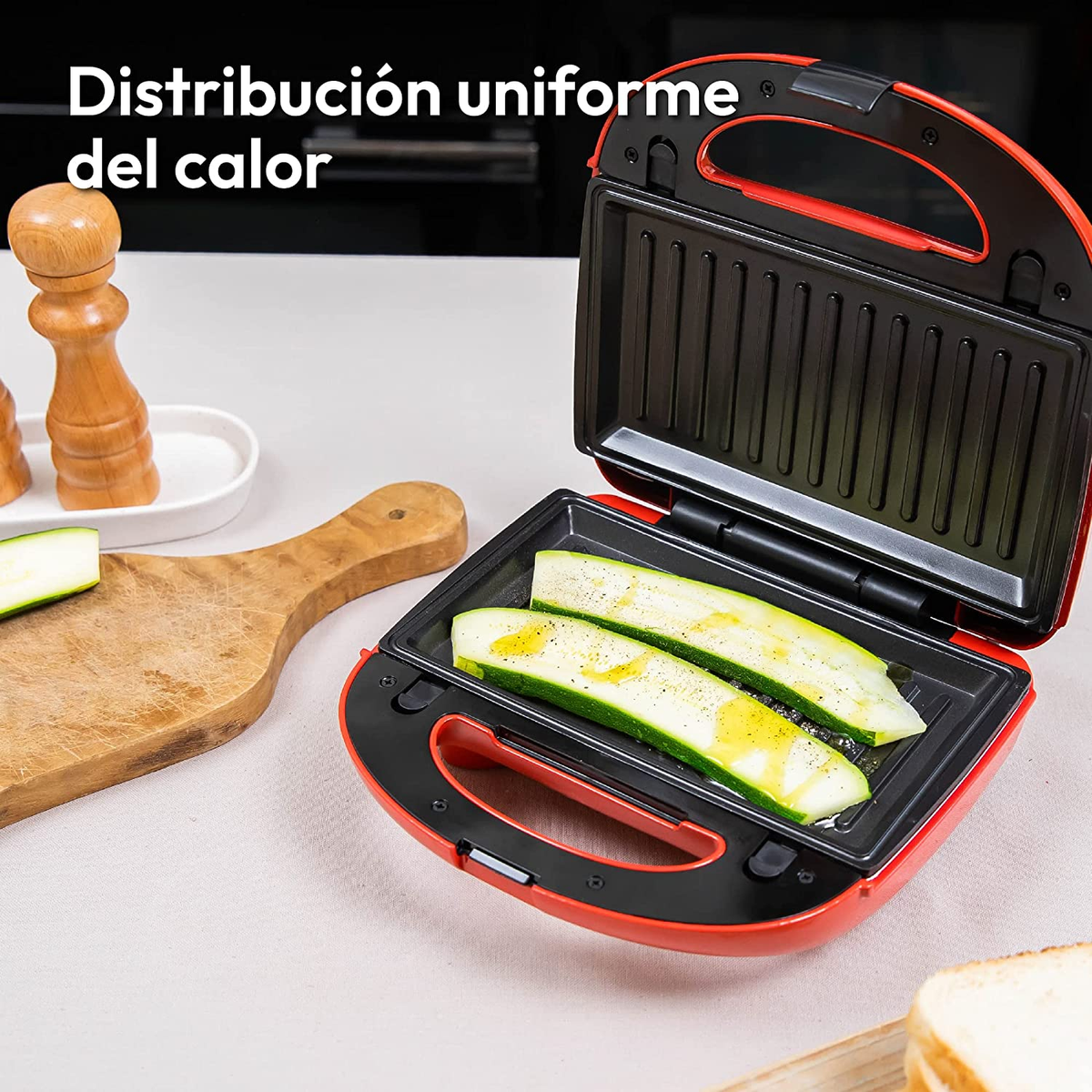 Toastiera rossa aperta con zucchine. Sfondo bianco, ambiente cucina.