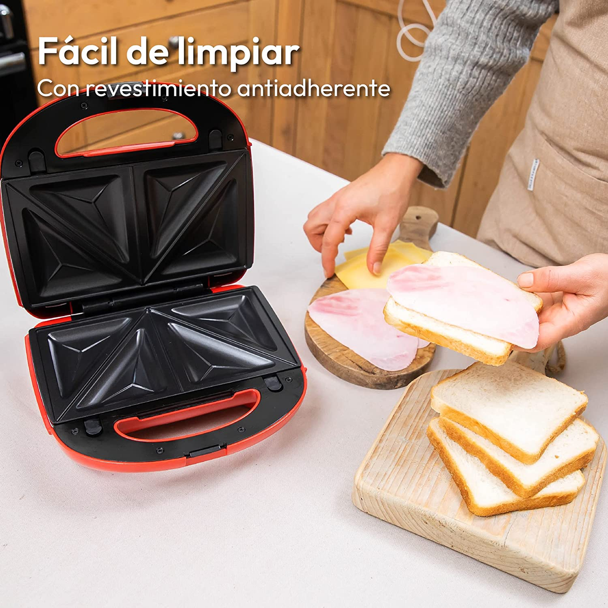 Macchina per sandwich aperta con panini dentro e ingredienti accanto.
