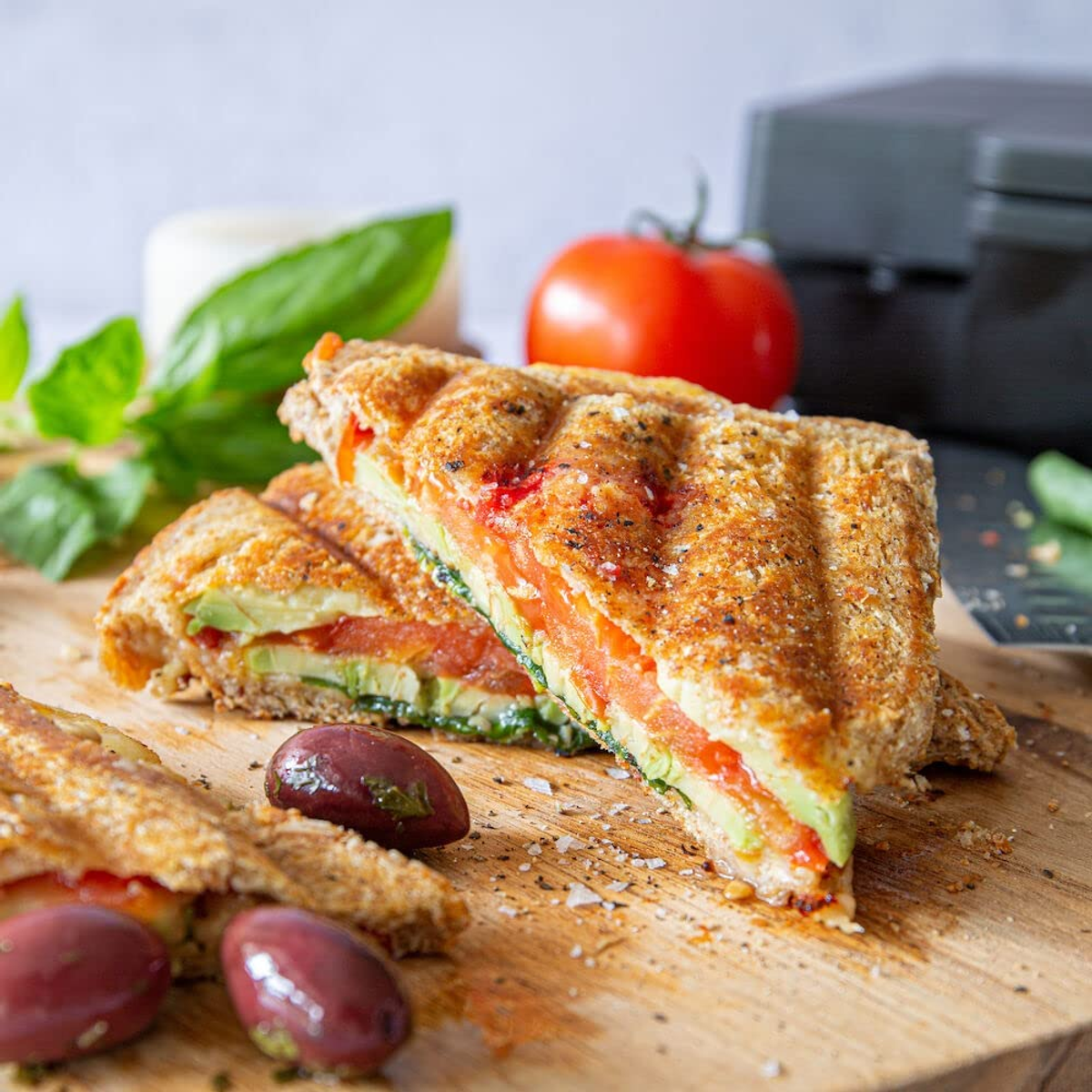 Gegrilltes Sandwich mit Avocado, Tomate und Basilikum, Nahaufnahme.