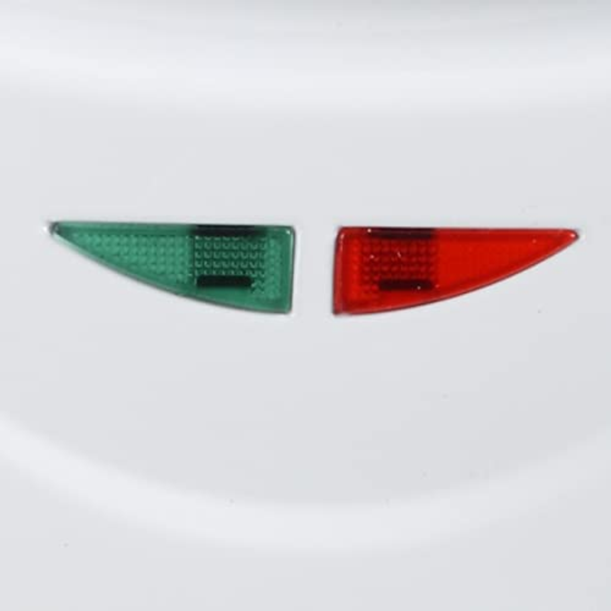 Primo piano delle luci di navigazione. Una luce verde e una rossa su una superficie bianca.