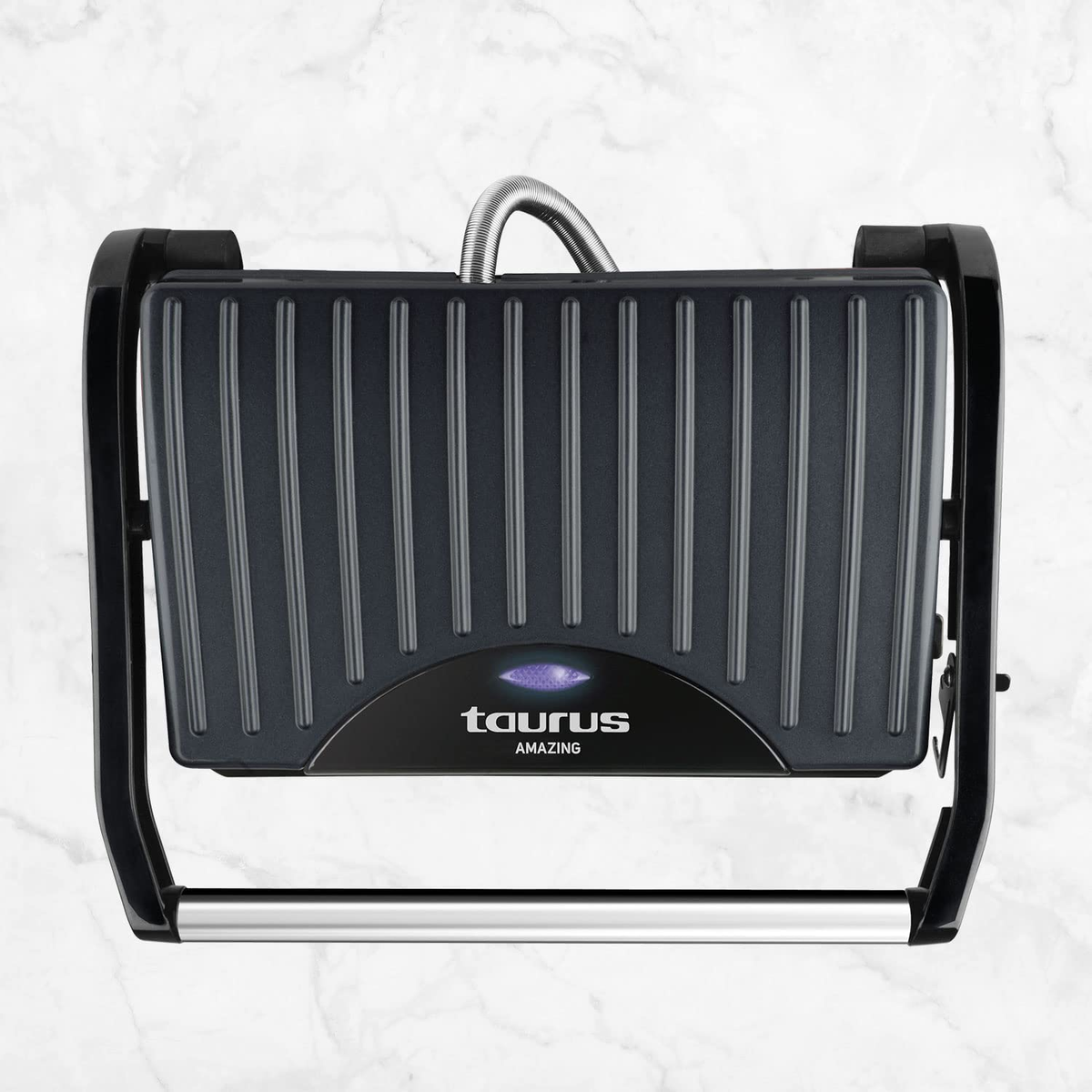 Una parrilla negra con el logo de Taurus, vista superior sobre mármol.