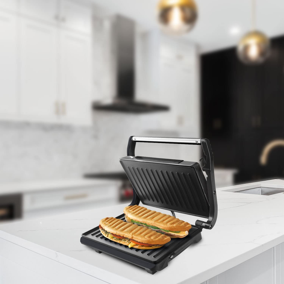 Una prensa para sándwiches negra con dos sándwiches. Los sándwiches están en una encimera blanca en una cocina.