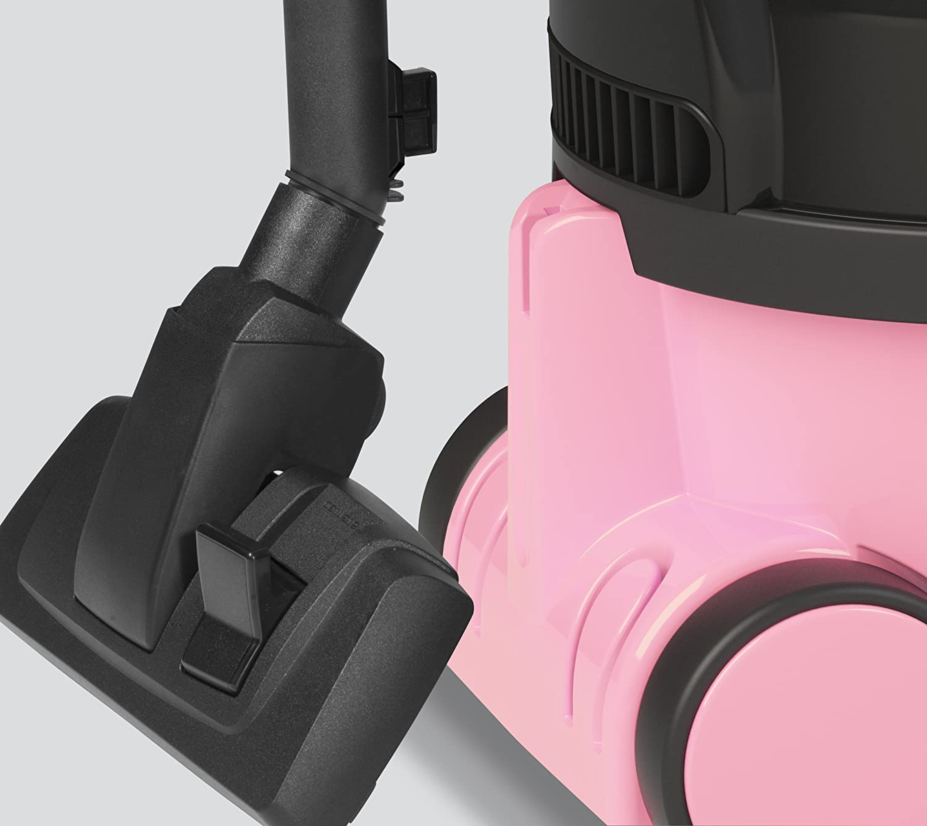 Zbliżenie różowego odkurzacza i jego szczotki na szarym tle.