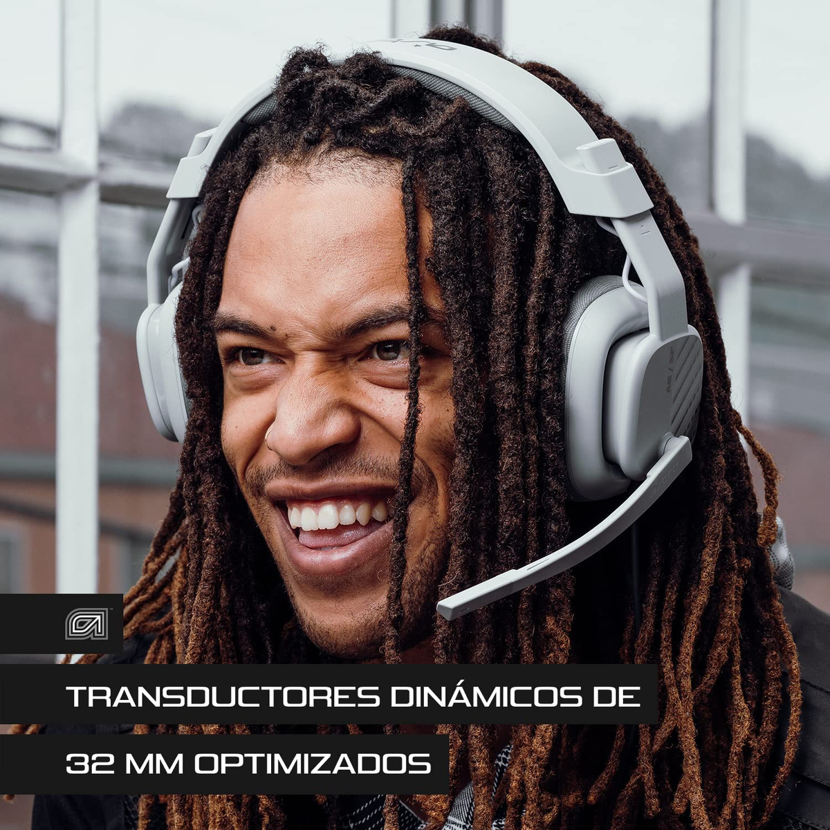 Mężczyzna z dredami w białym zestawie słuchawkowym do gier, uśmiechnięty i patrzący w górę. Tekst o sterownikach dynamicznych.