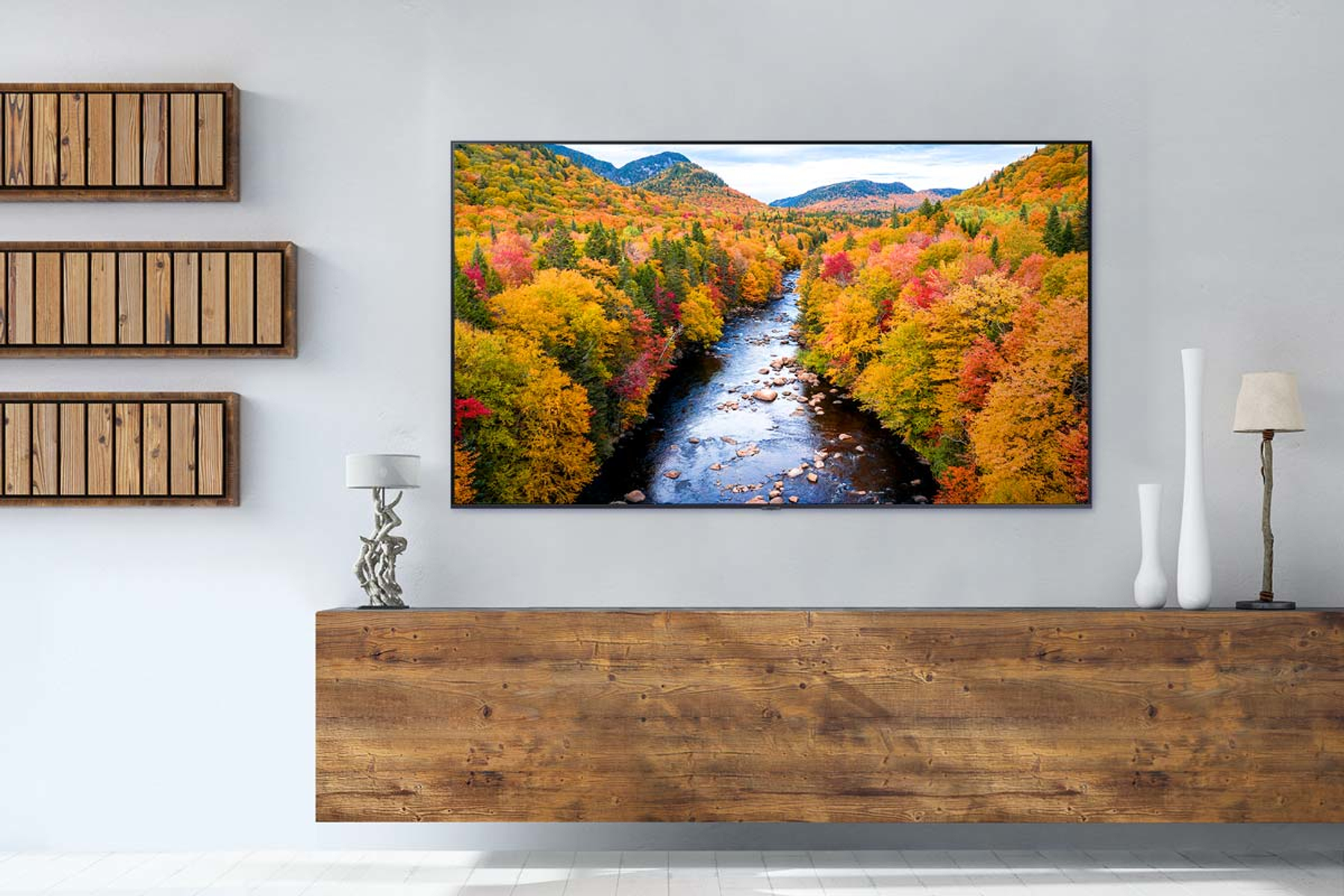 Vista panoramica di un fiume tra alberi autunnali colorati. TV montata su superficie in legno.
