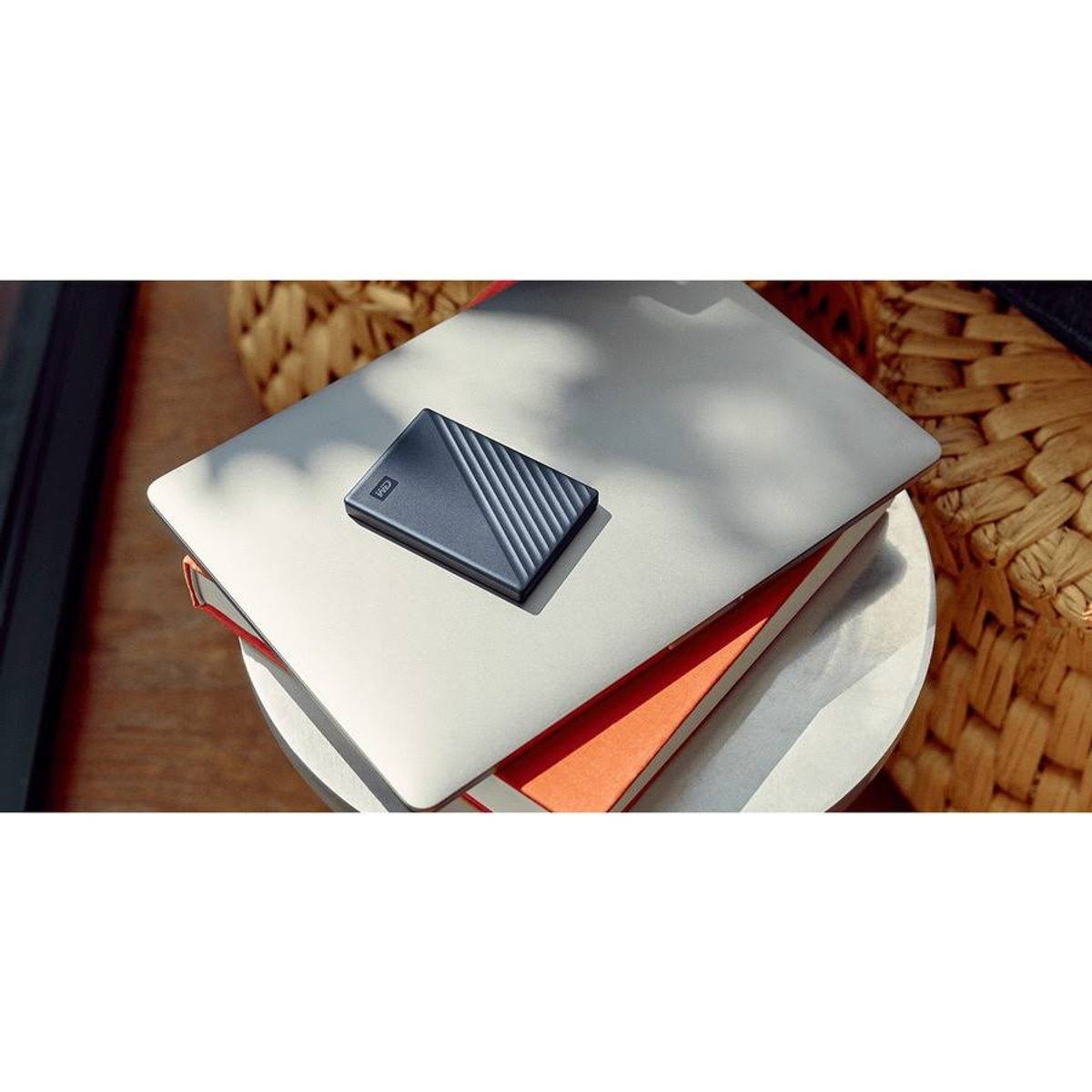 Dysk twardy na laptopie i notatnik na stole. Tło jest rozmyte.