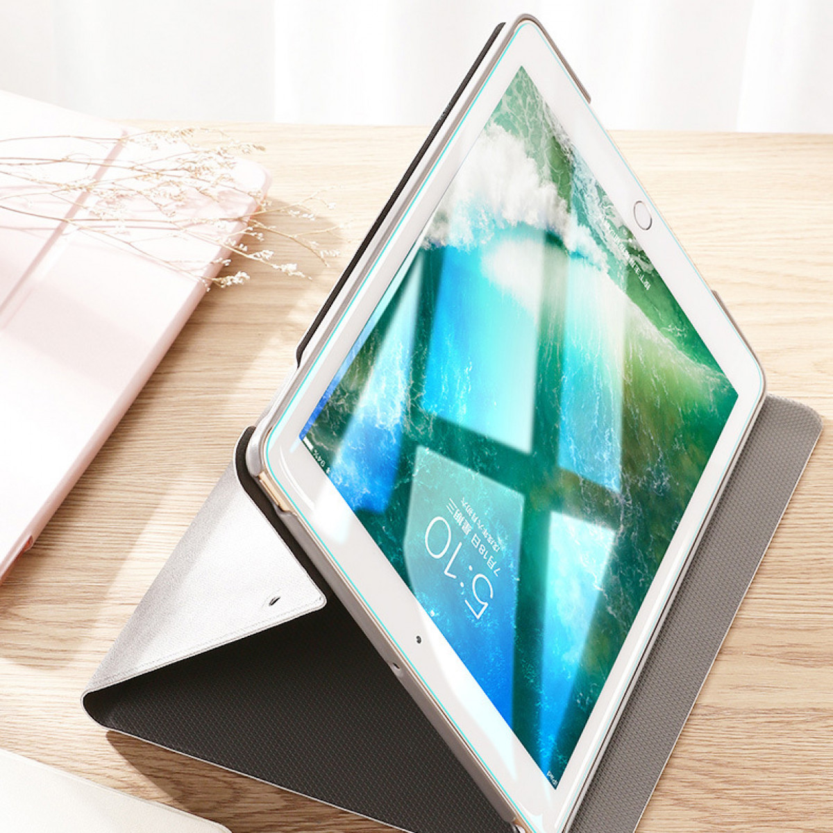 Tablet in custodia, aperto su tavolo di legno. Sfondo sfocato.