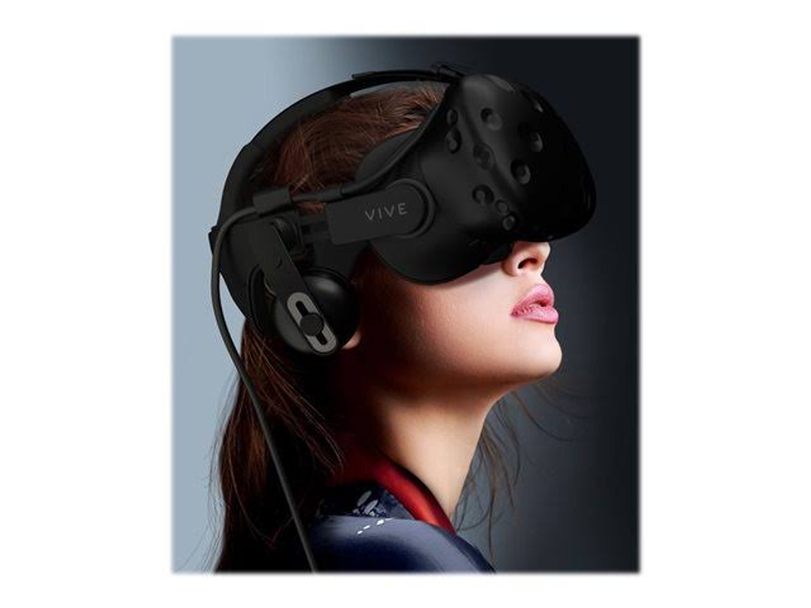 Mujer con auriculares de realidad virtual negros. Los auriculares tienen la palabra VIVE. Mujer mirando hacia arriba.