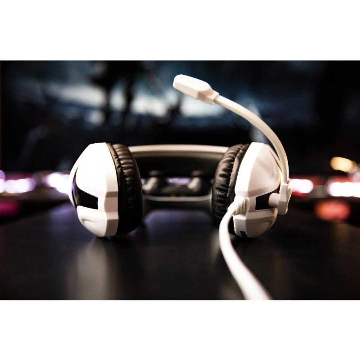 Biały zestaw słuchawkowy do gier z mikrofonem. Jest na ciemnej powierzchni, tło jest rozmyte.