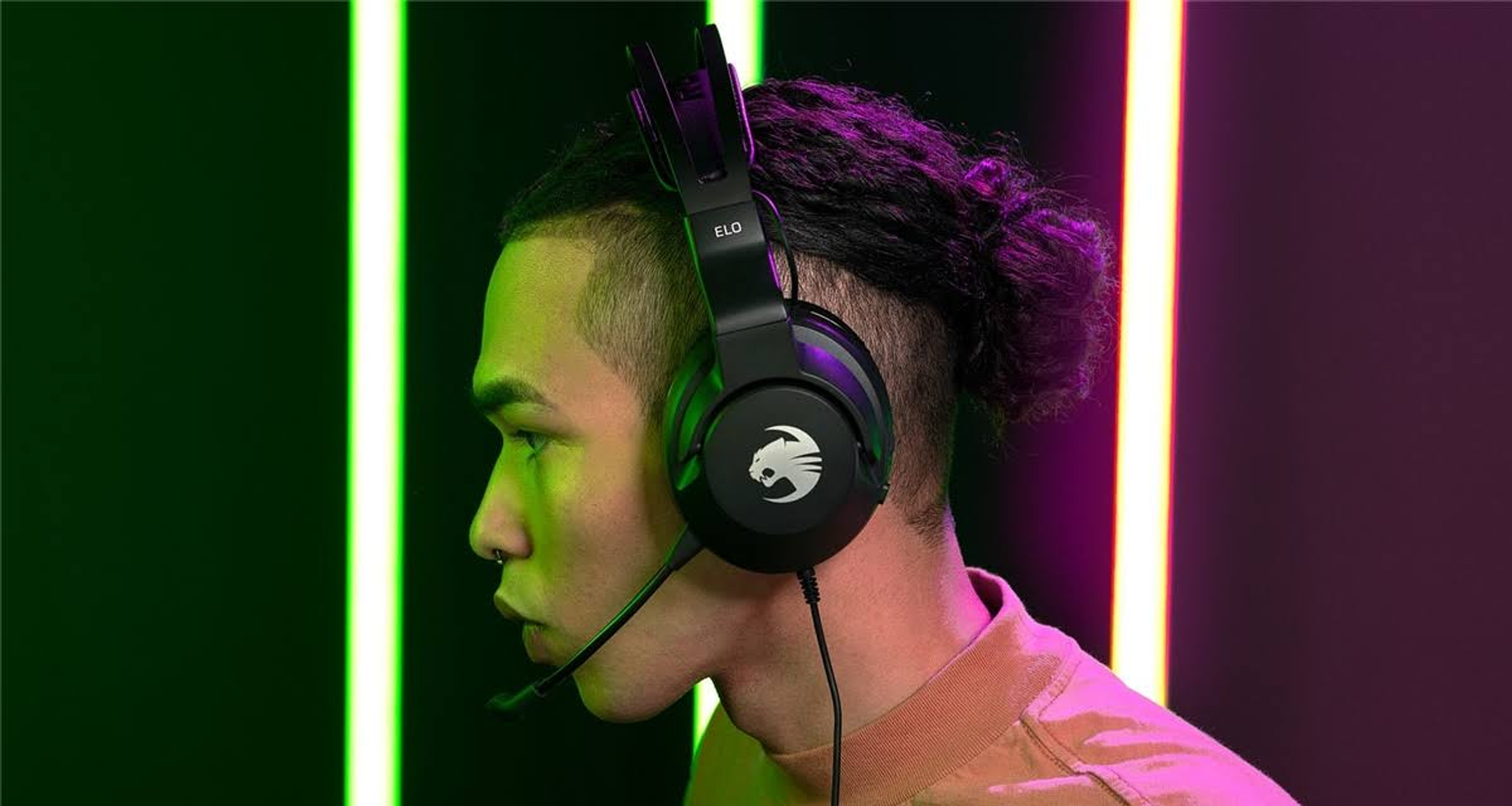 Mann trägt schwarzes Gaming-Headset mit Mikrofon. Grüner und violetter Hintergrund.