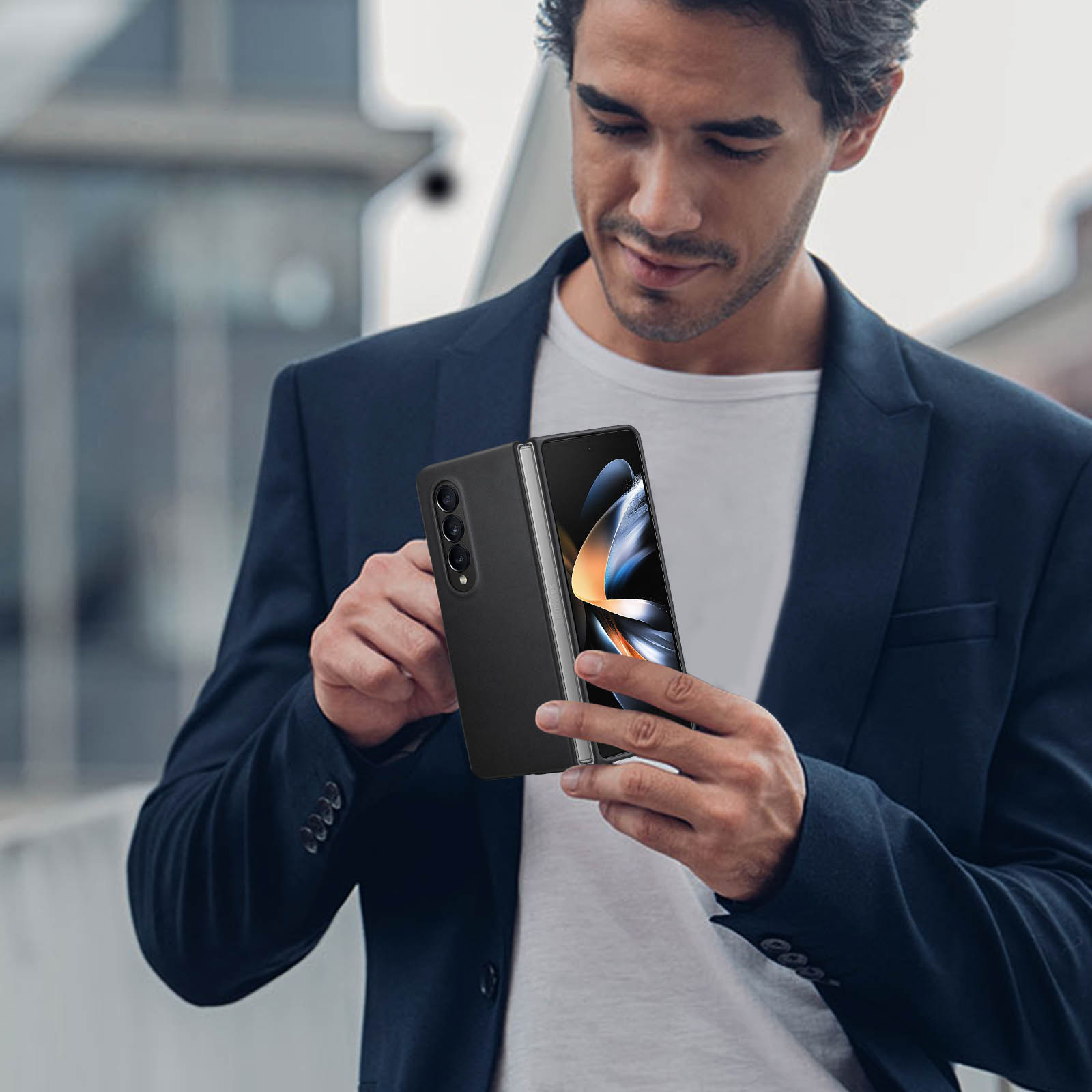 Un hombre sosteniendo un teléfono plegable negro. Lleva un traje oscuro.