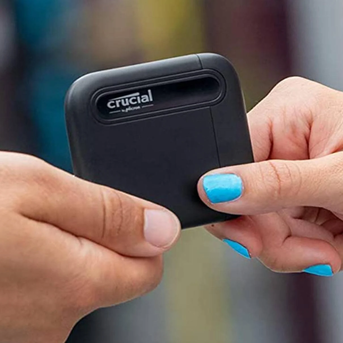 Dłonie trzymające czarny zewnętrzny dysk twardy Crucial.