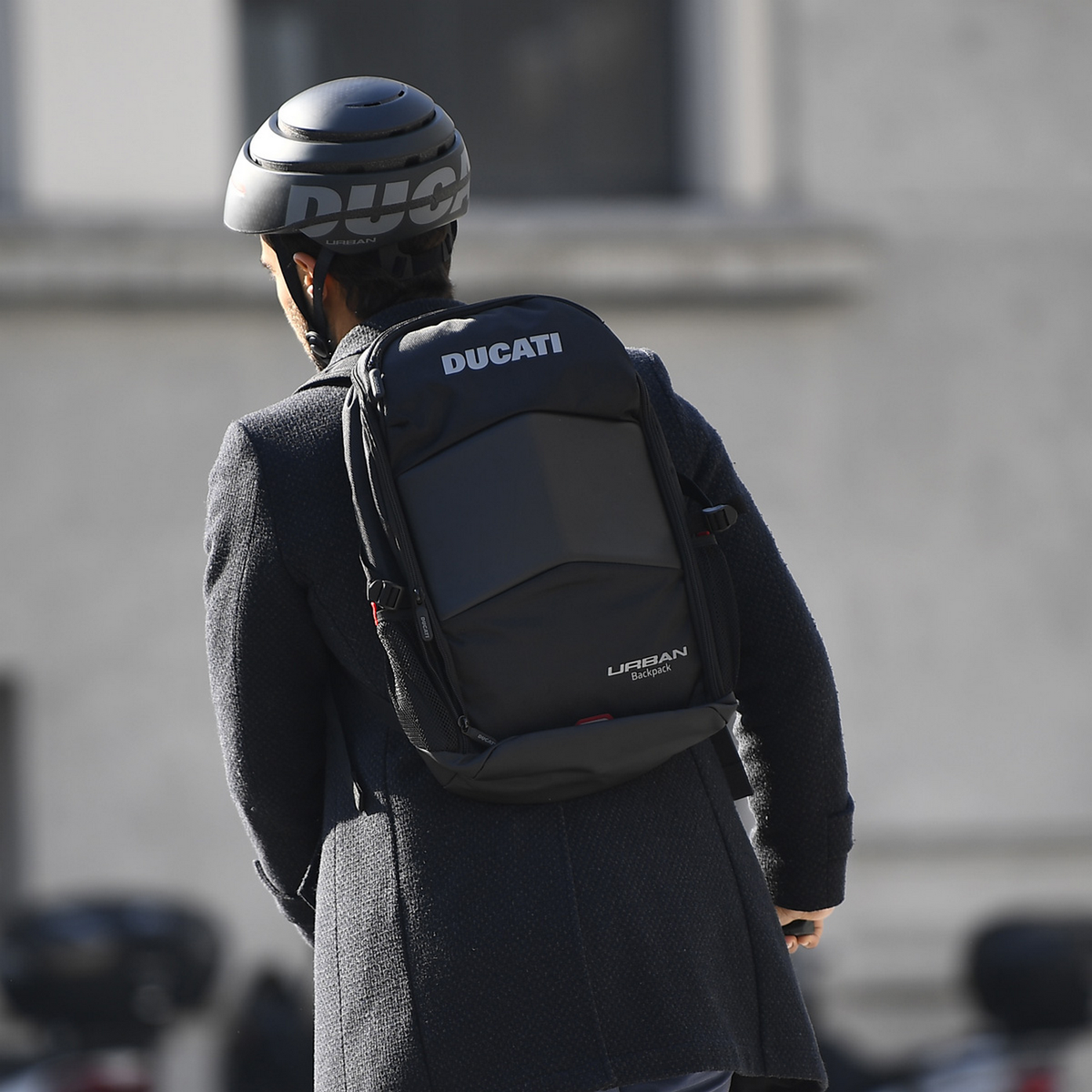 Osoba w kasku i z plecakiem z logo Ducati.