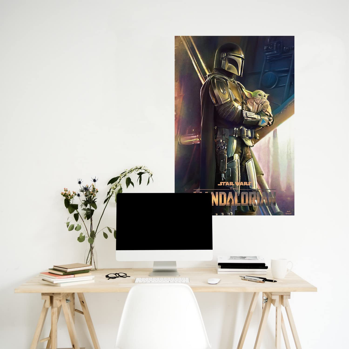 Un póster de Mandalorian y Grogu, en un escritorio con computadora, flores y libros.