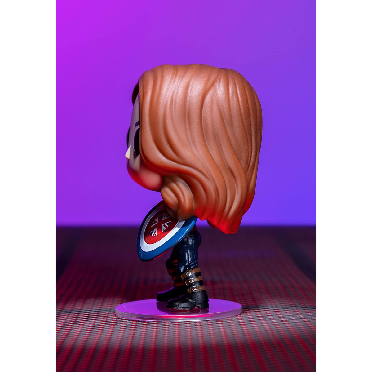 Funko Pop di una donna che tiene uno scudo. Ha i capelli rossi e si trova su uno sfondo viola.