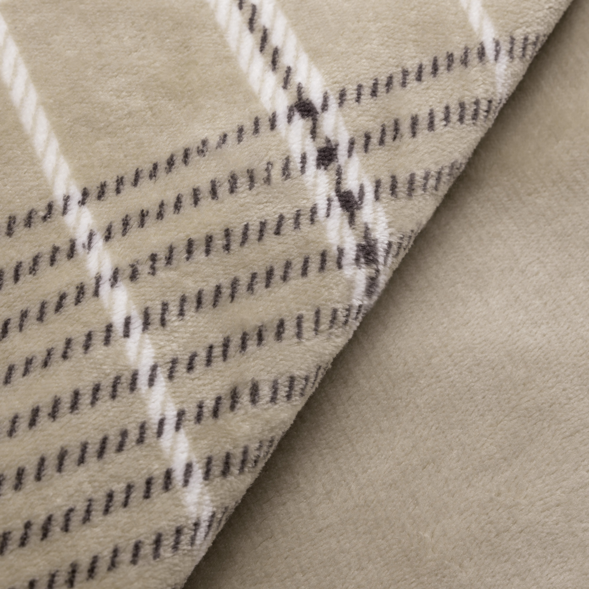 Zbliżenie beżowego koca we wzór w kratę. Koc jest złożony.