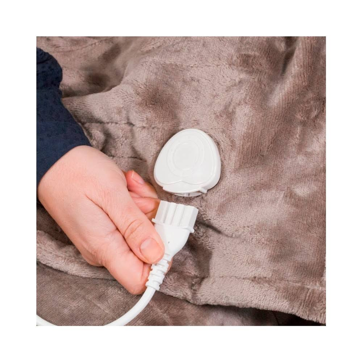 Dłoń trzymająca białą wtyczkę podłączoną do brązowego koca.