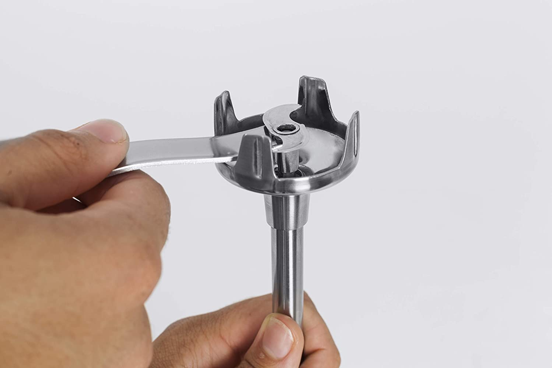 Hand hält eine Metallklinge. Die Klinge ist an der Basis eines Mixers befestigt.