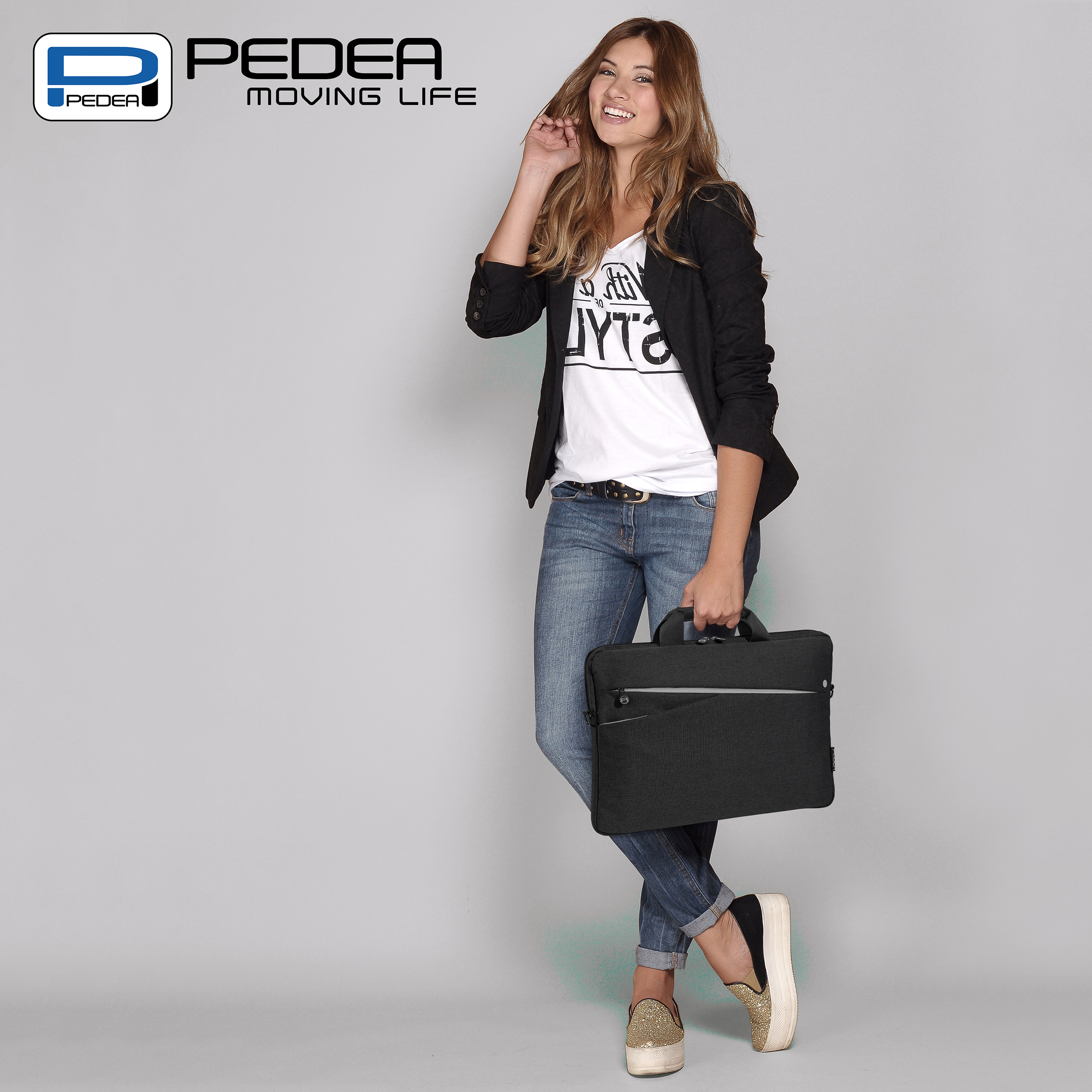 Donna con borsa per laptop sorride, con blazer e jeans.