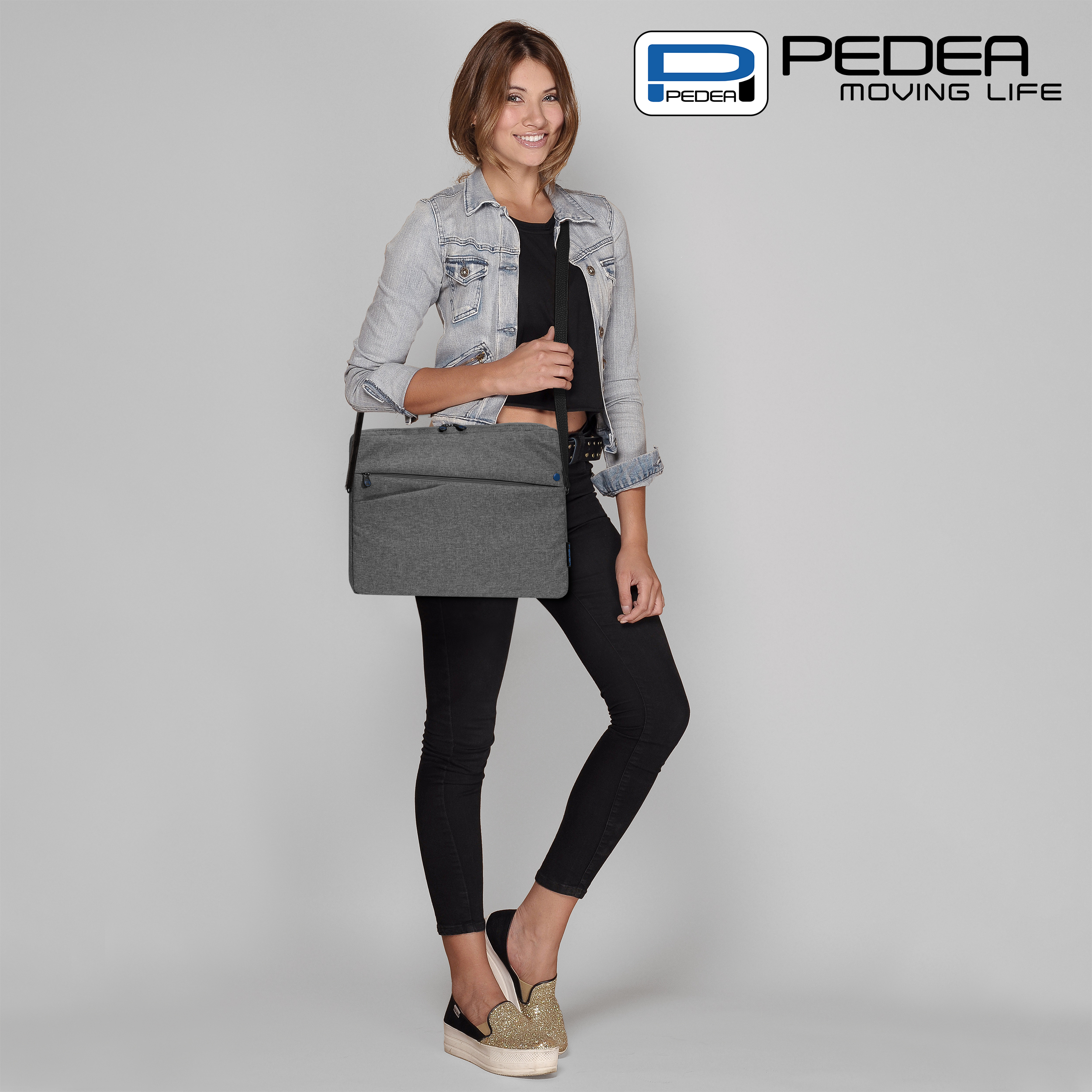 Una donna con giacca di jeans e pantaloni neri porta una borsa grigia.