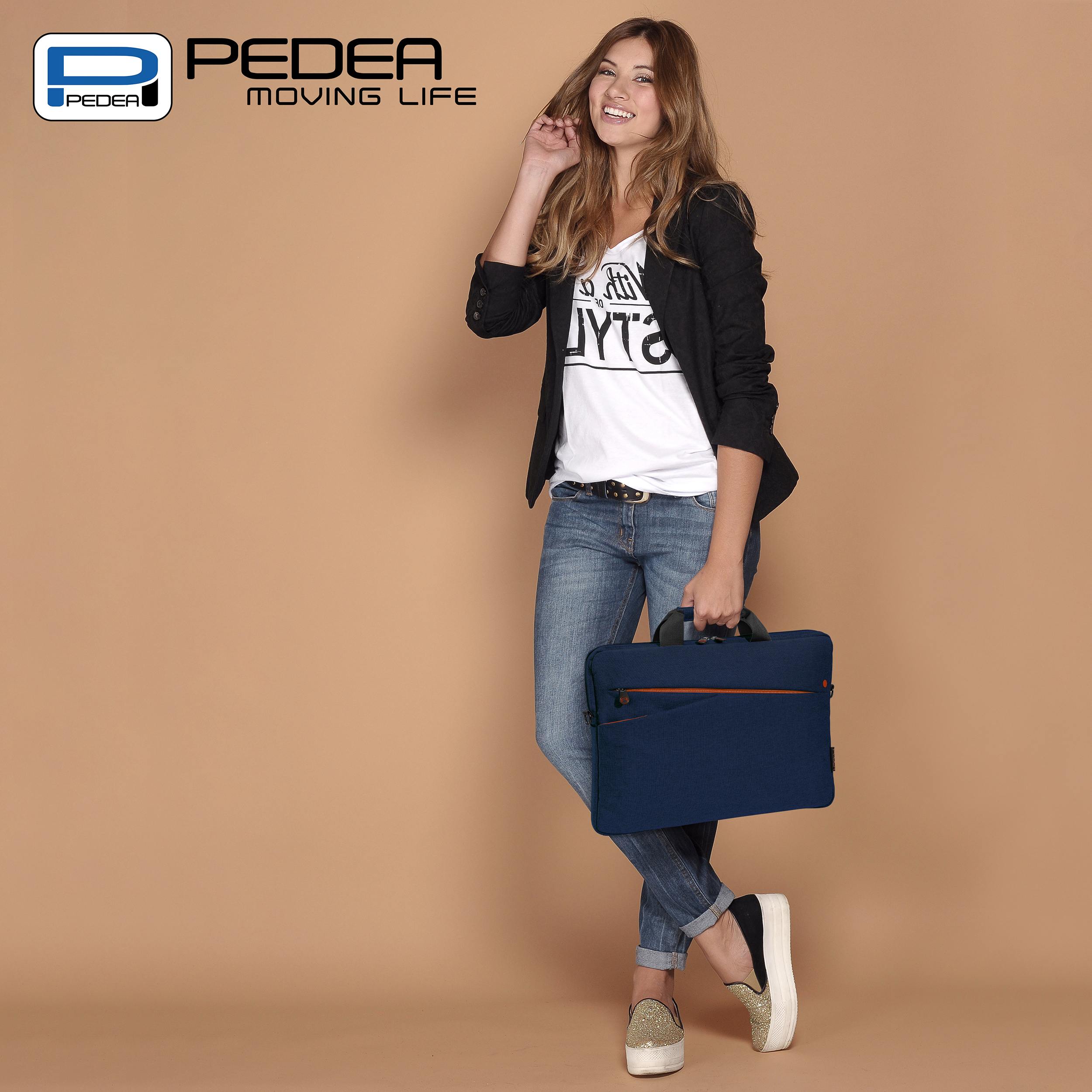 Donna con maglietta bianca e jeans che tiene una borsa blu per laptop. Sorride ed è in piedi.