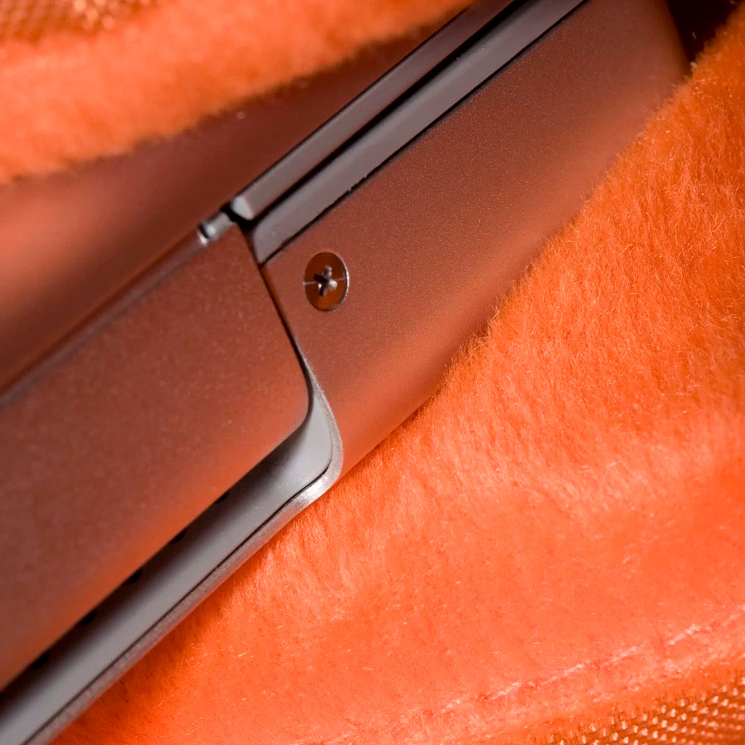 Nahaufnahme einer teilweise geöffneten Laptoptaste auf einer orangefarbenen, flauschigen Oberfläche.