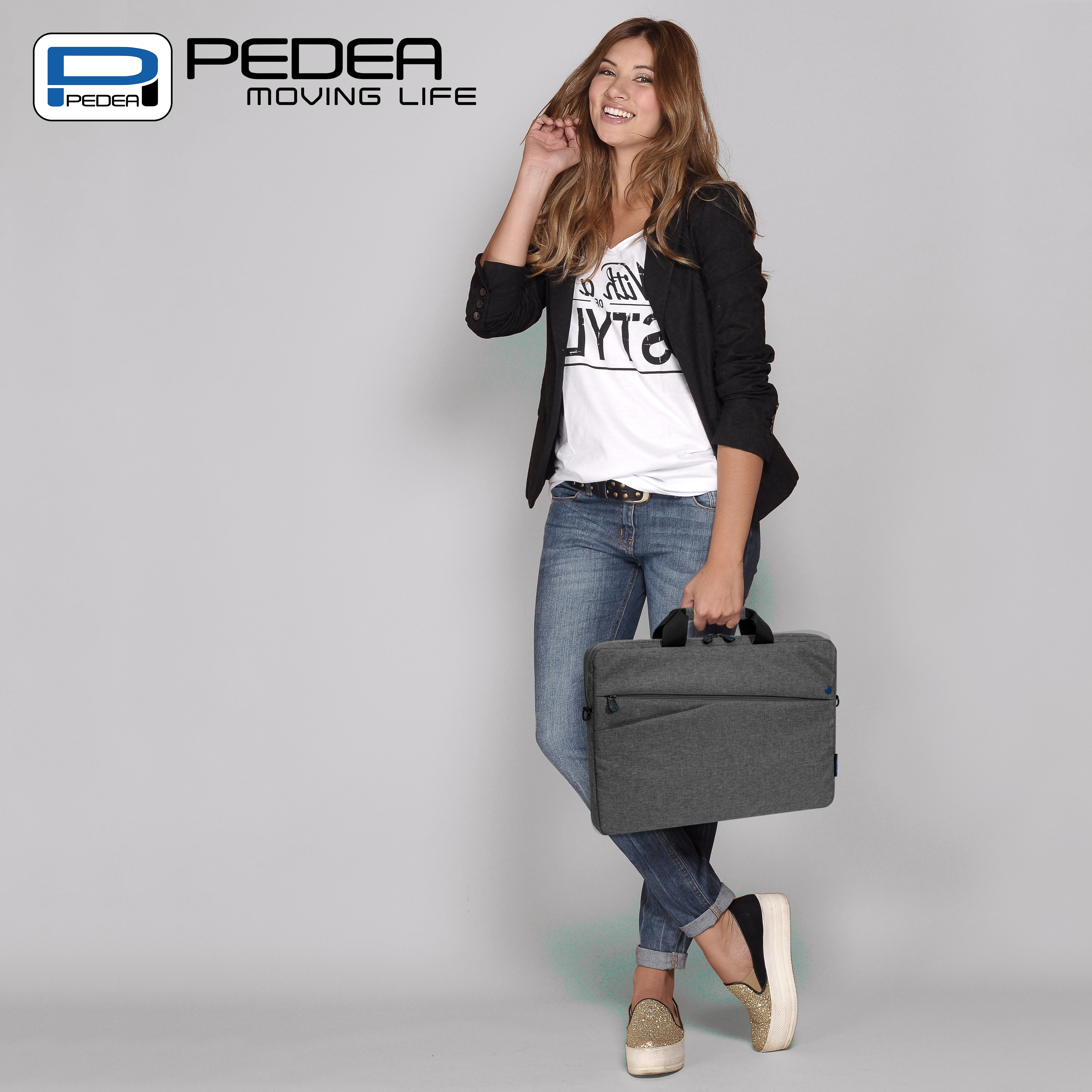 Eine Frau hält eine graue Laptoptasche und trägt ein weißes Hemd, Jeans und eine schwarze Jacke.