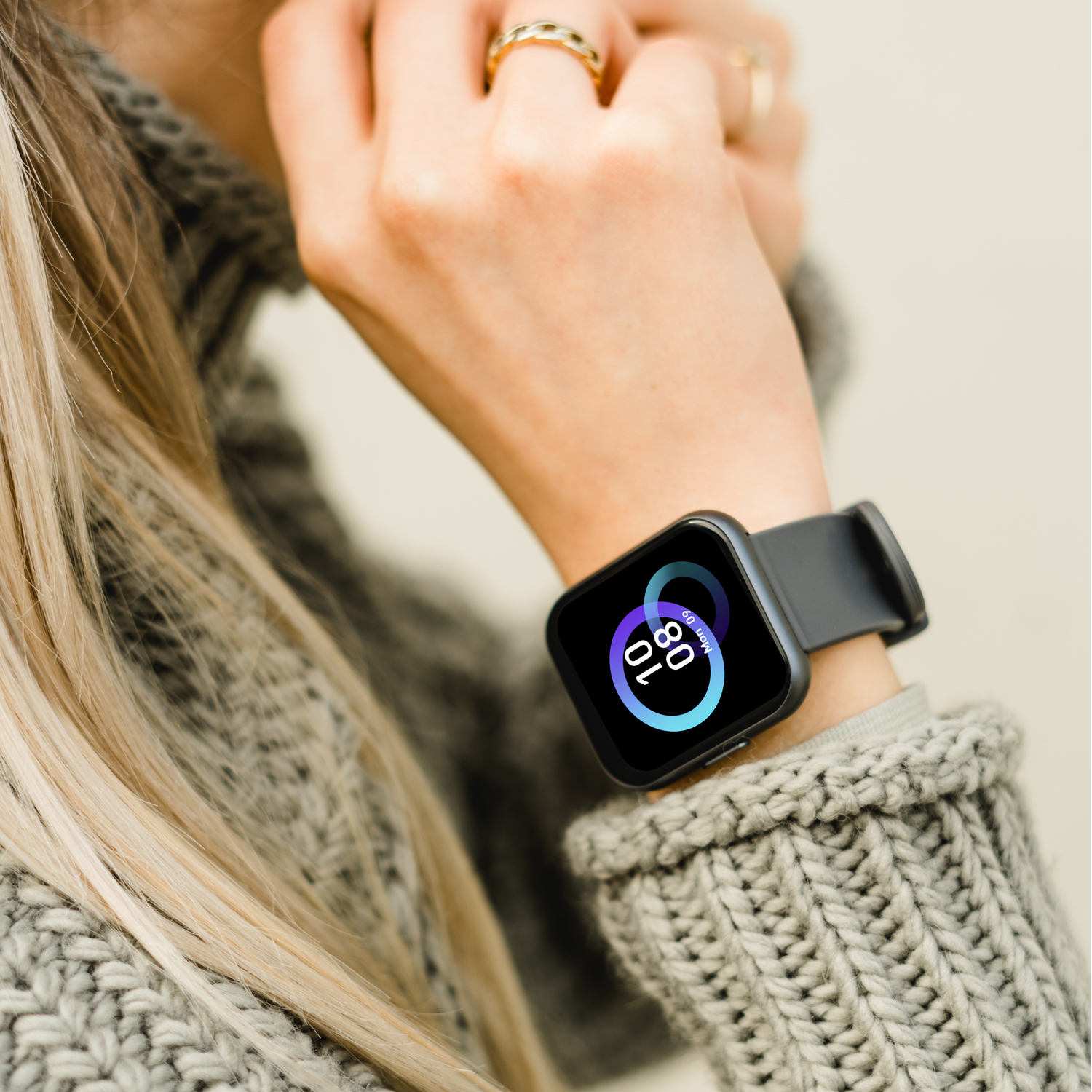 Das Handgelenk einer Person mit einer schwarzen Smartwatch, die Zeit und Datum anzeigt.