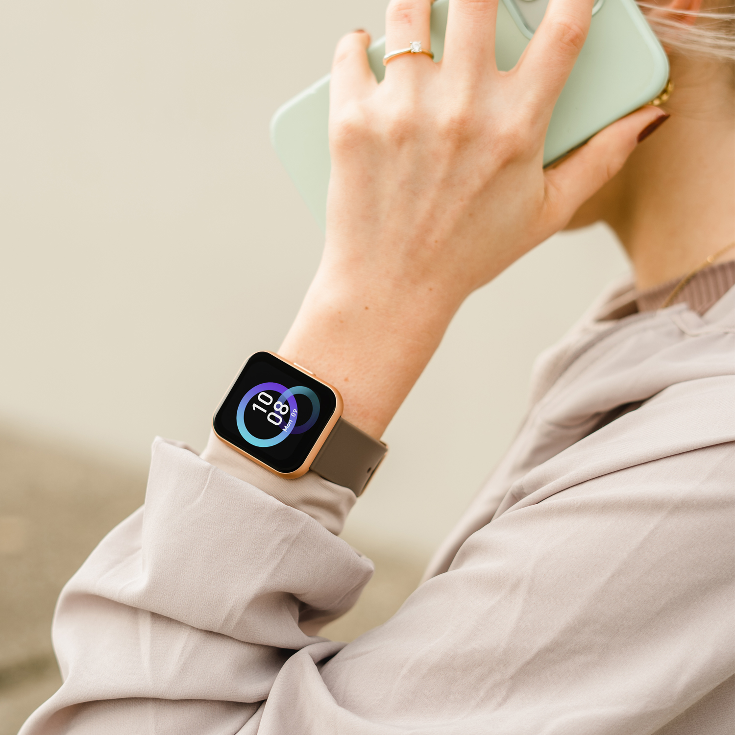 Kobieta nosząca smartwatch, trzyma telefon blisko ucha.