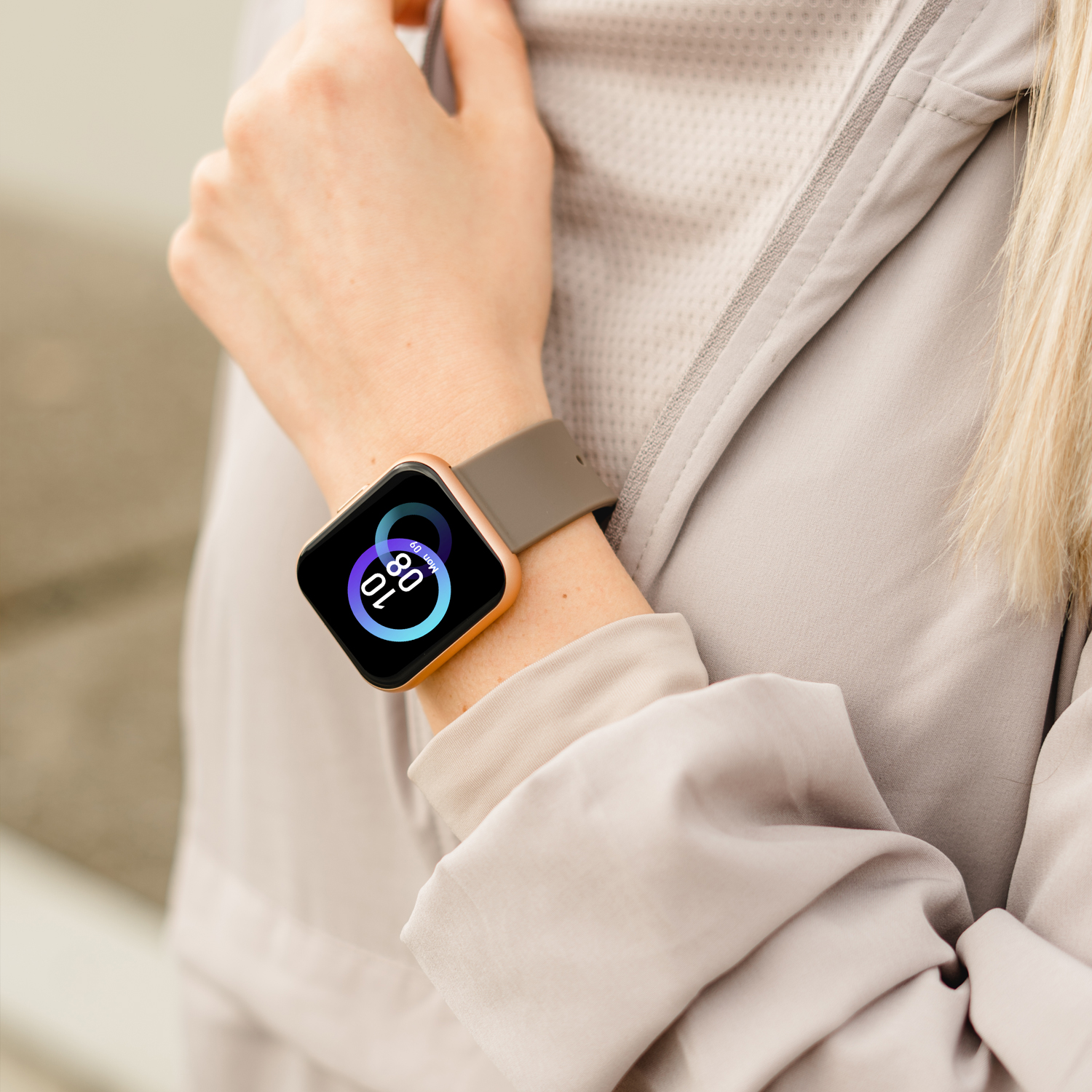 Osoba nosząca smartwatch. Zegarek pokazuje 10:08 i 80% baterii. Złota ramka, szary pasek.