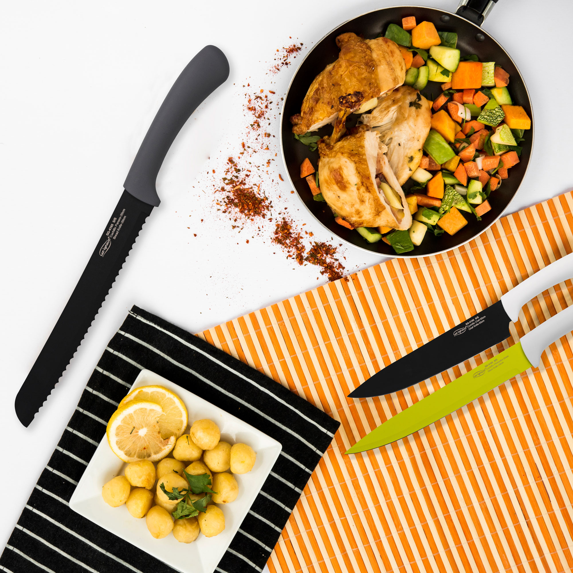 Una escena de cocina con una sartén con pollo y verduras, un plato de comida y cuchillos.