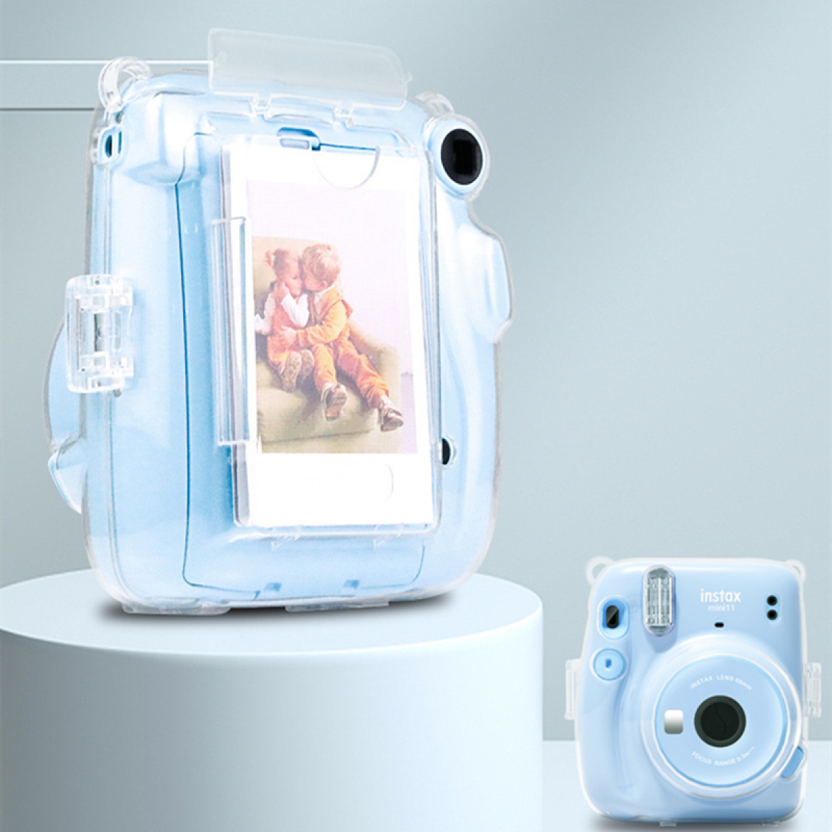Eine blaue Instax-Kamera in einer transparenten Hülle, mit einer kleineren Kamera rechts.