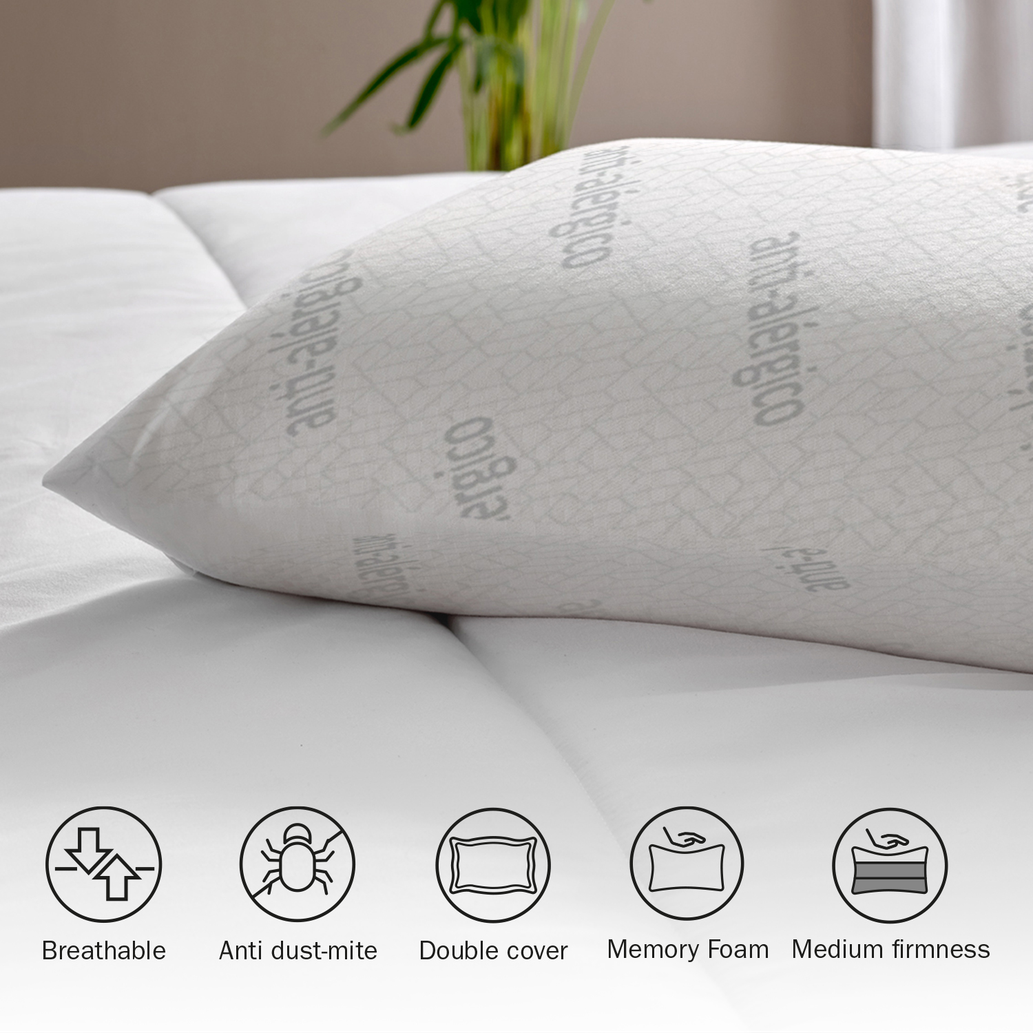 Una almohada blanca con texto e iconos antialérgicos. Está en una cama blanca.