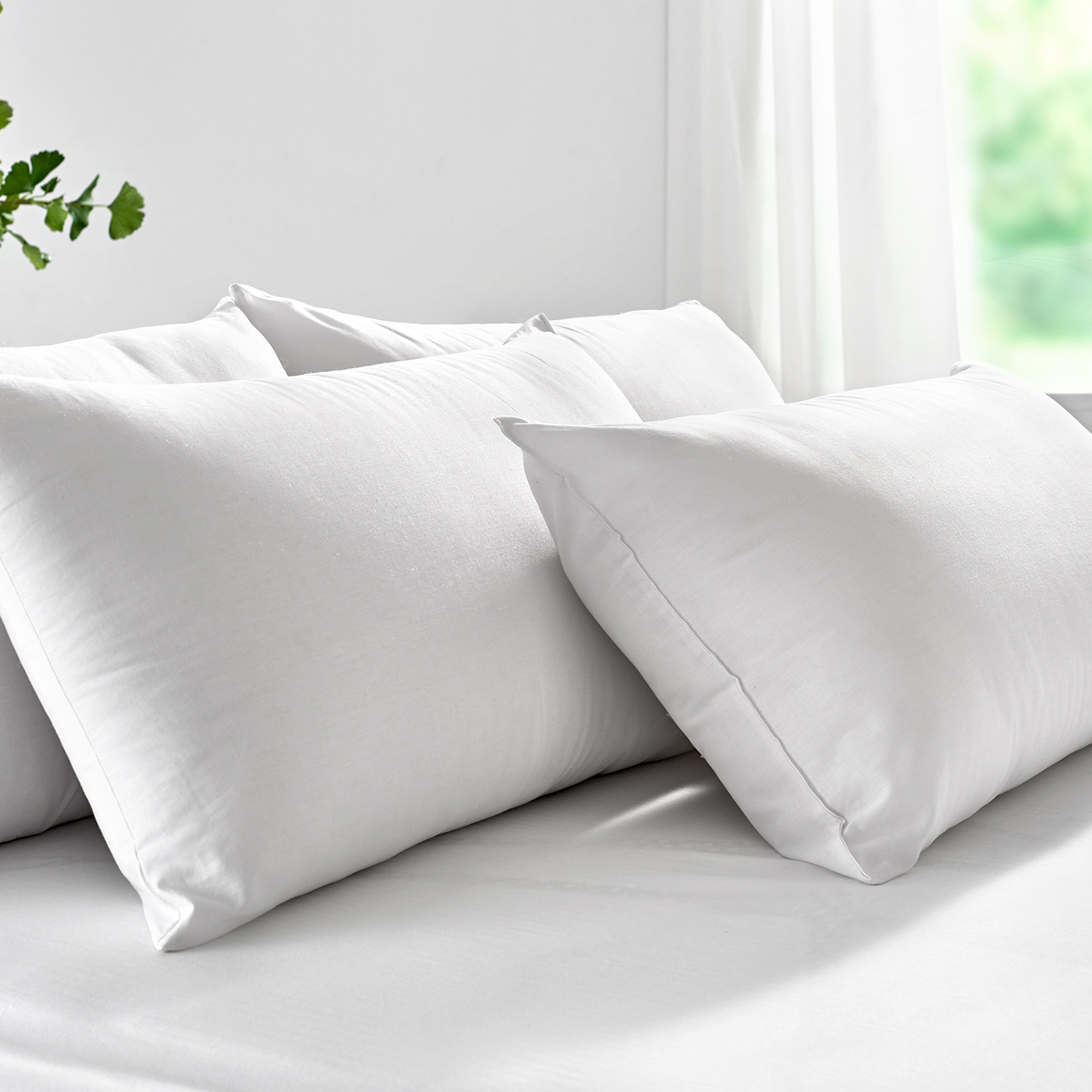 Cuatro almohadas blancas en una cama. Las almohadas son suaves, rectangulares y claras.