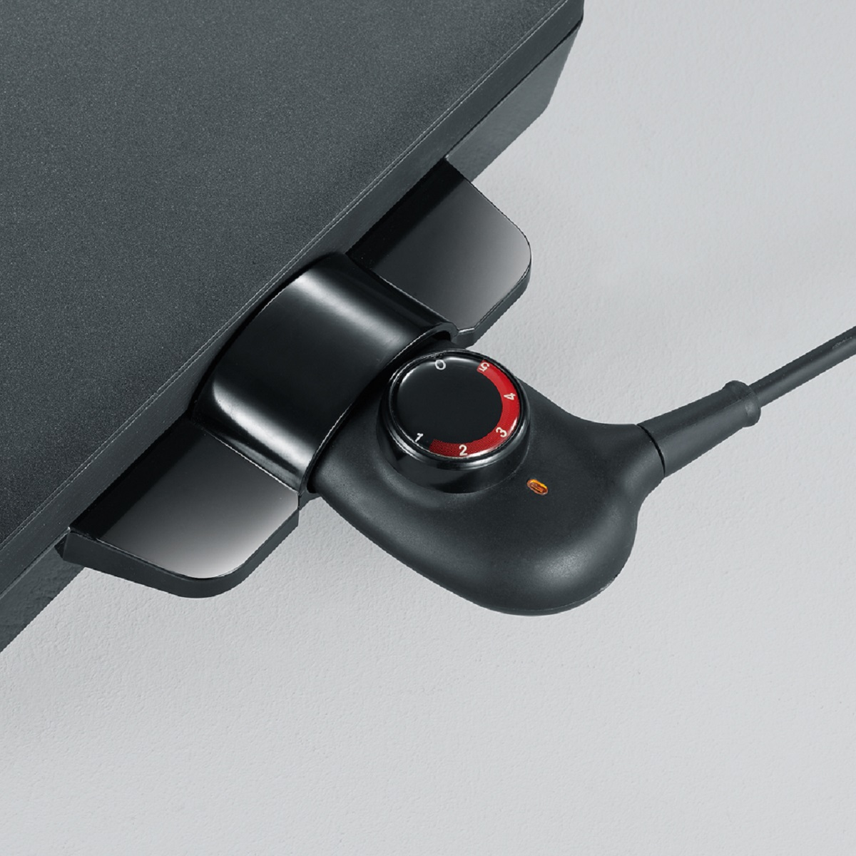 Pannello di controllo nero con un quadrante numerato da 0 a 5 e una spia rossa, collegato a un elettrodomestico nero.