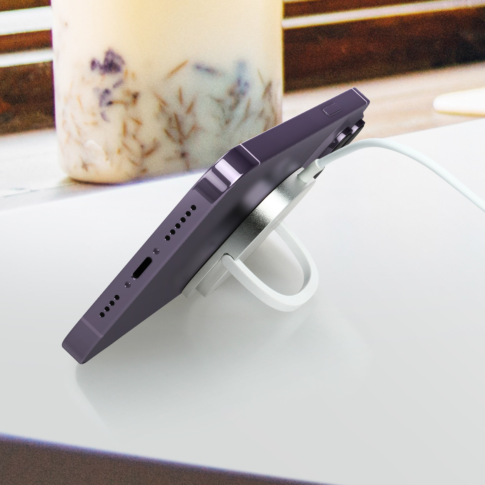 Telefono viola su supporto bianco, con cavo di ricarica bianco.
