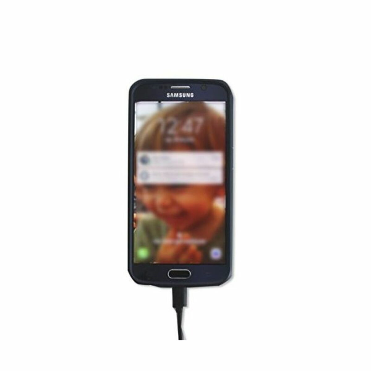 Uno smartphone nero in carica, mostra il volto sfocato di un bambino.