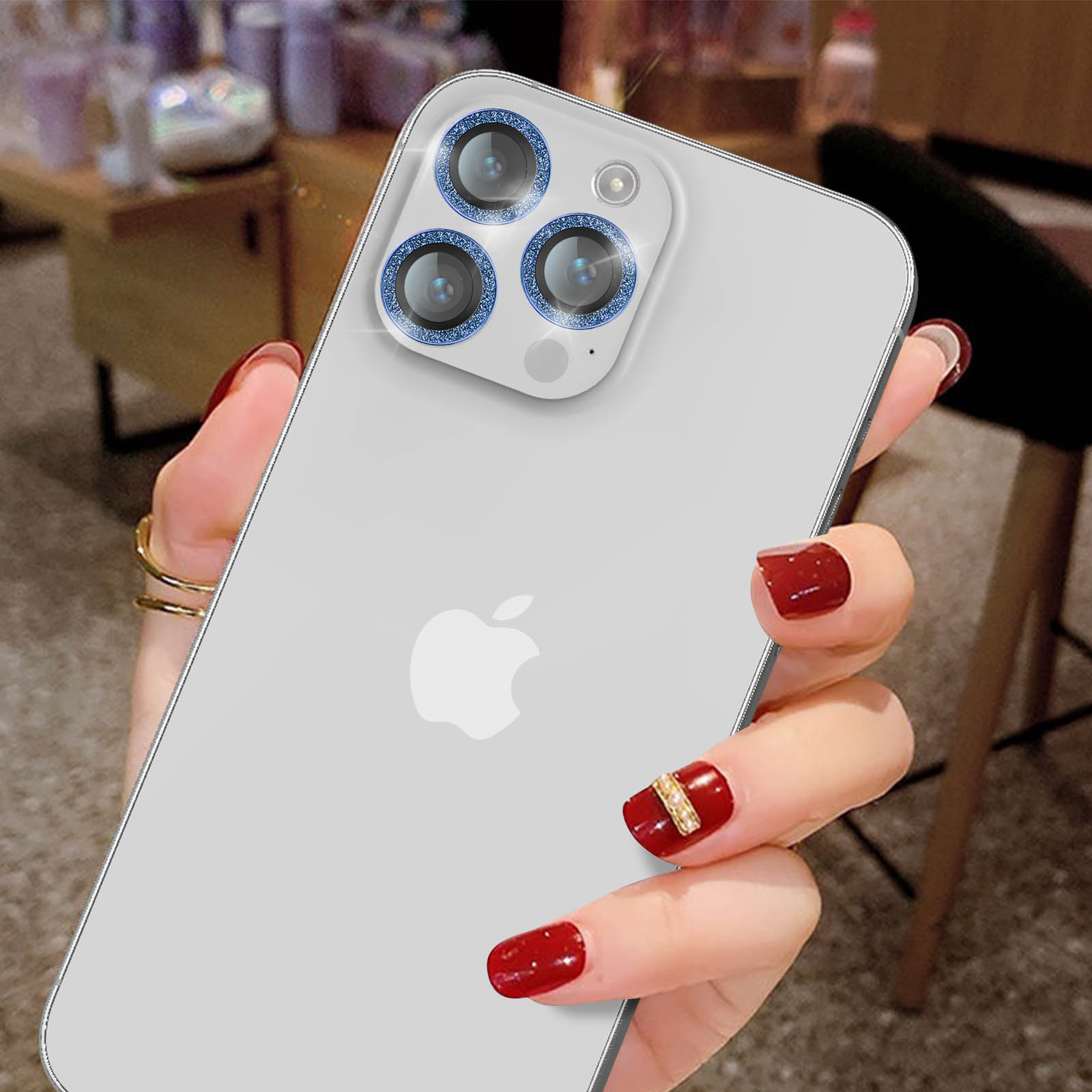 Mano di donna con unghie rosse che tiene un iPhone bianco con tre lenti blu e un logo Apple.