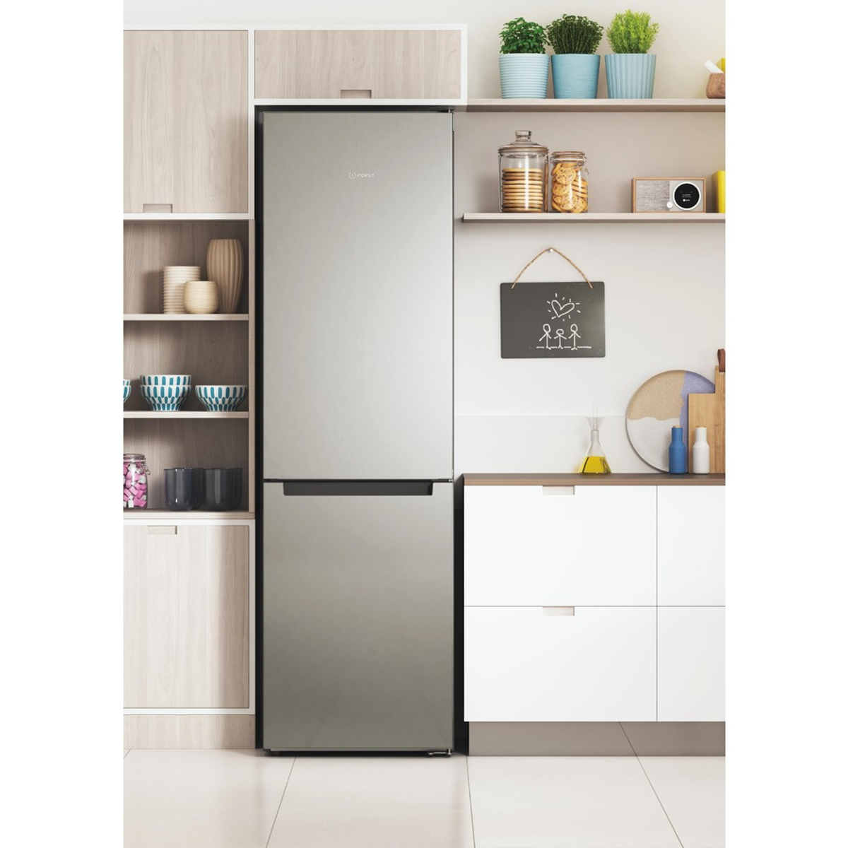 Lodówka ze stali nierdzewnej w otoczeniu kuchennym. Różne przedmioty kuchenne na półkach.